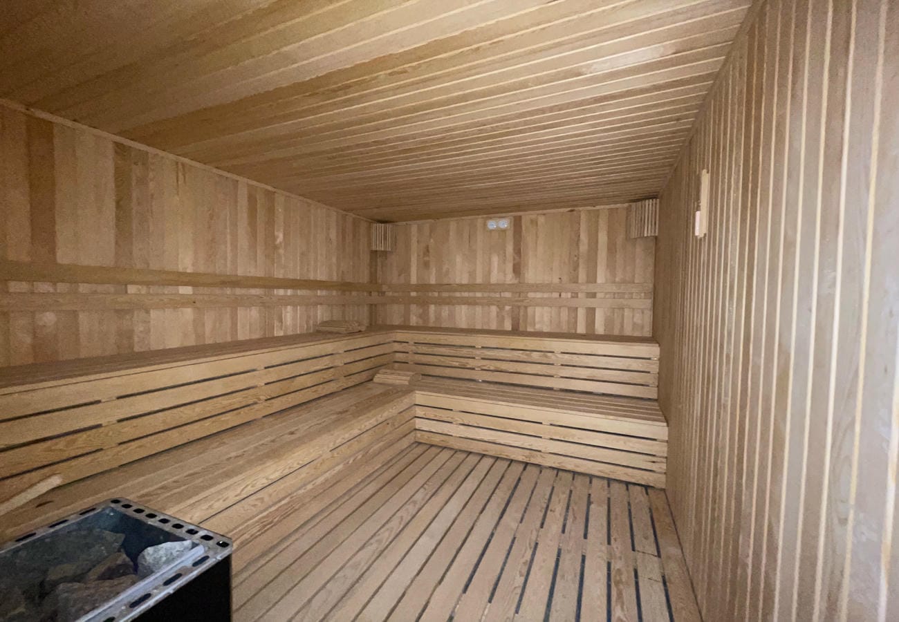 Sauna with tiered wooden benches, timber walls and a stone heater in Mahmutlar