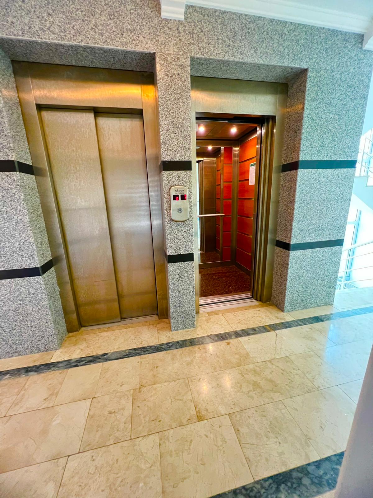 Lobide iki asansör, mermer duvarlar ve koyu detaylı mermer zeminle Türkiye’de