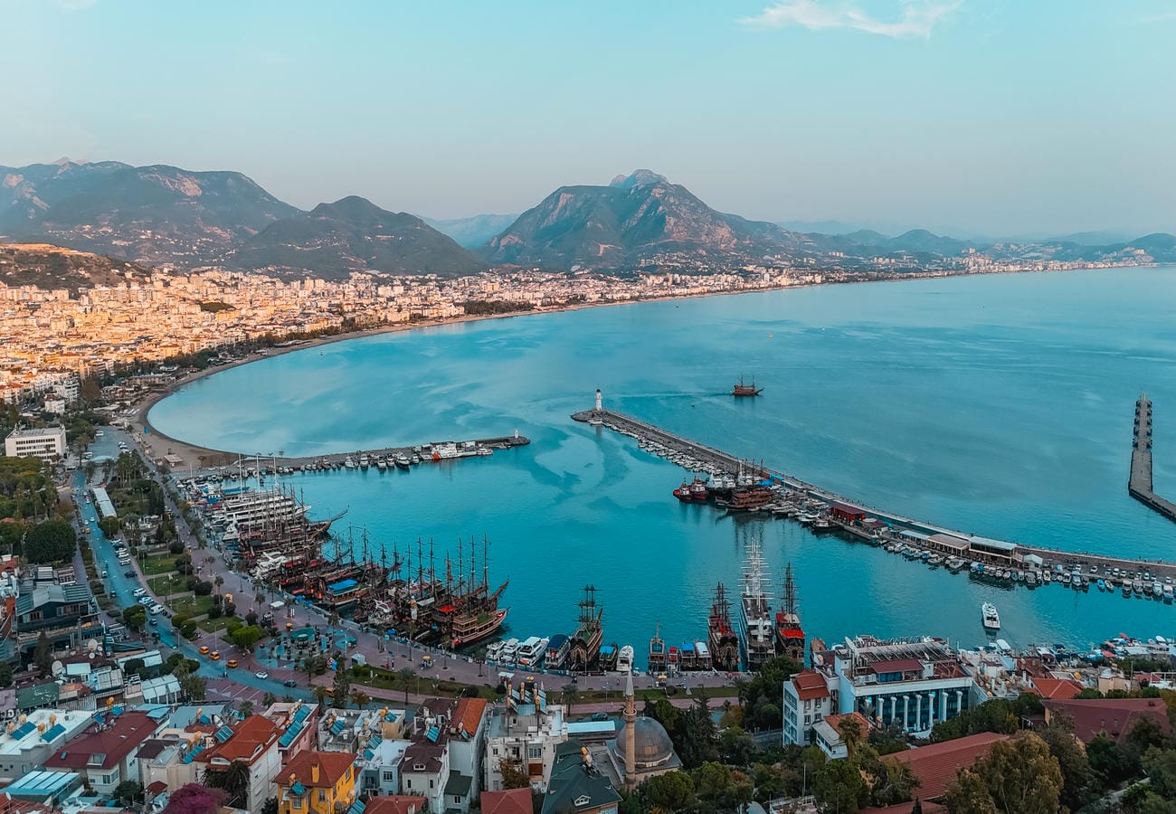 Wide bay with a city beach, port and coastal mountain range surrounds apartments in Türkiye