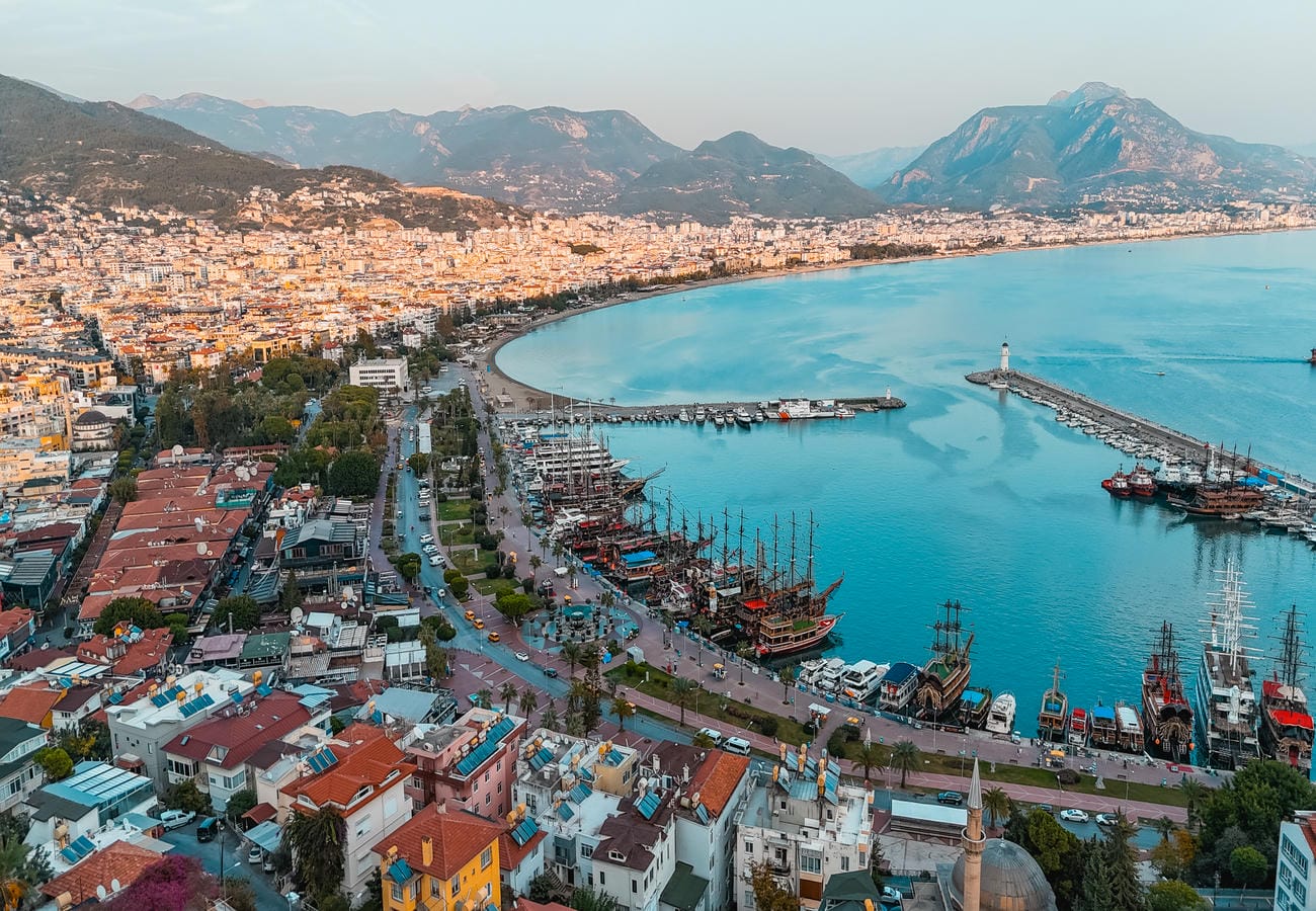 Turquoise bay with piers, boats and a mosque lies among the coastal urban landscape