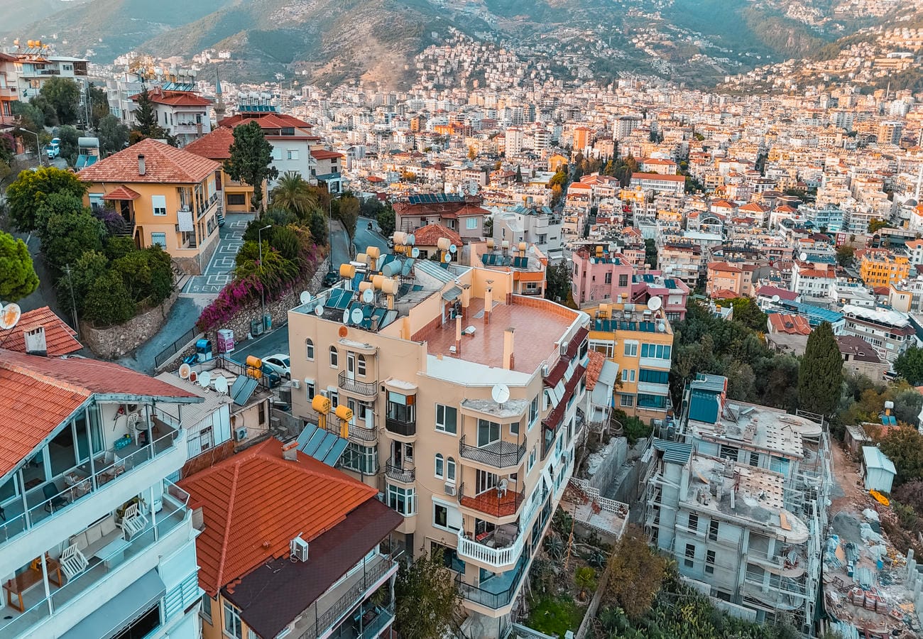 Dense hillside city with solar panels and a concrete frame shows an apartment for sale in Alanya