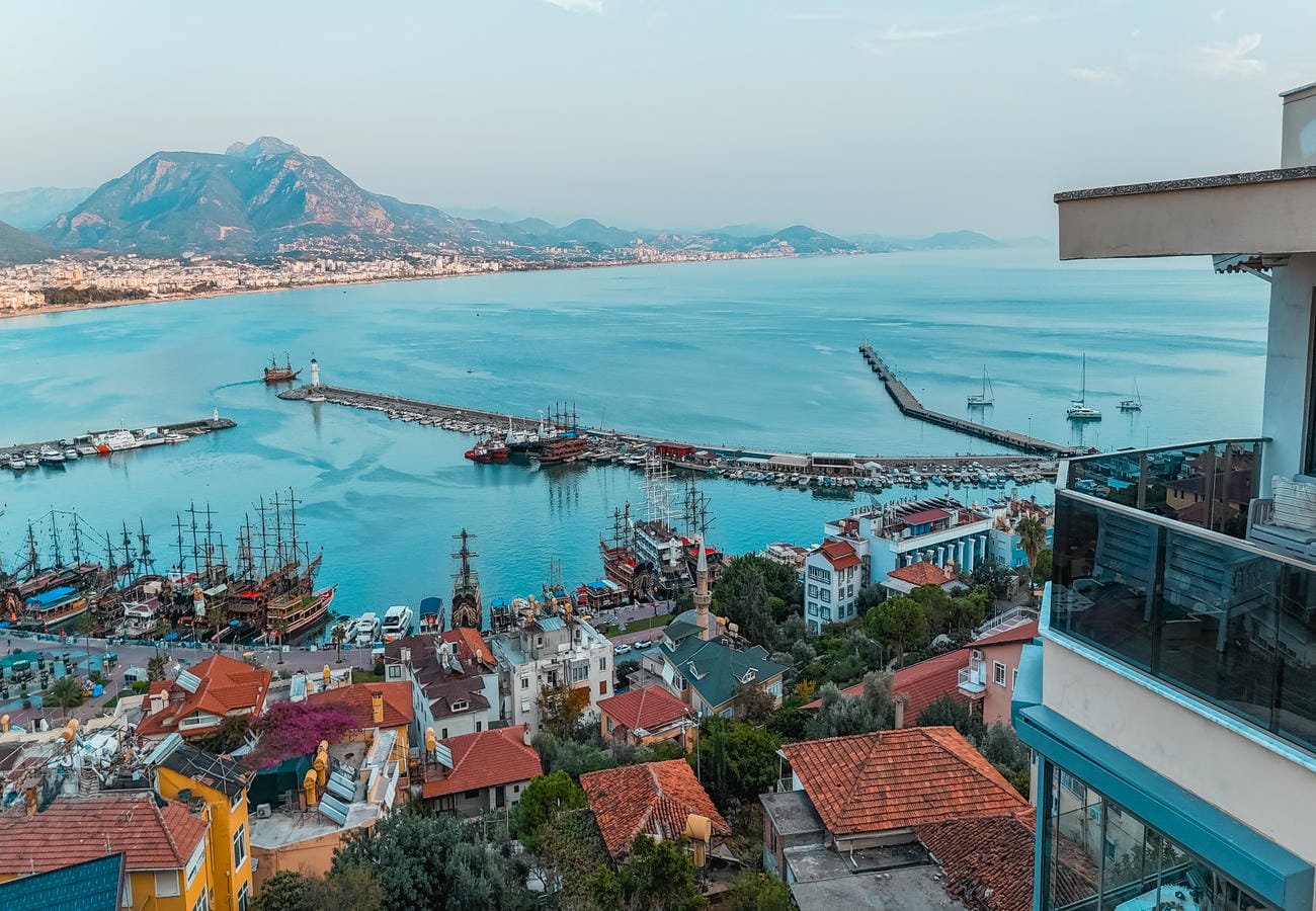 Panoramic bay with port piers and sailing ships presents flats for sale in Türkiye