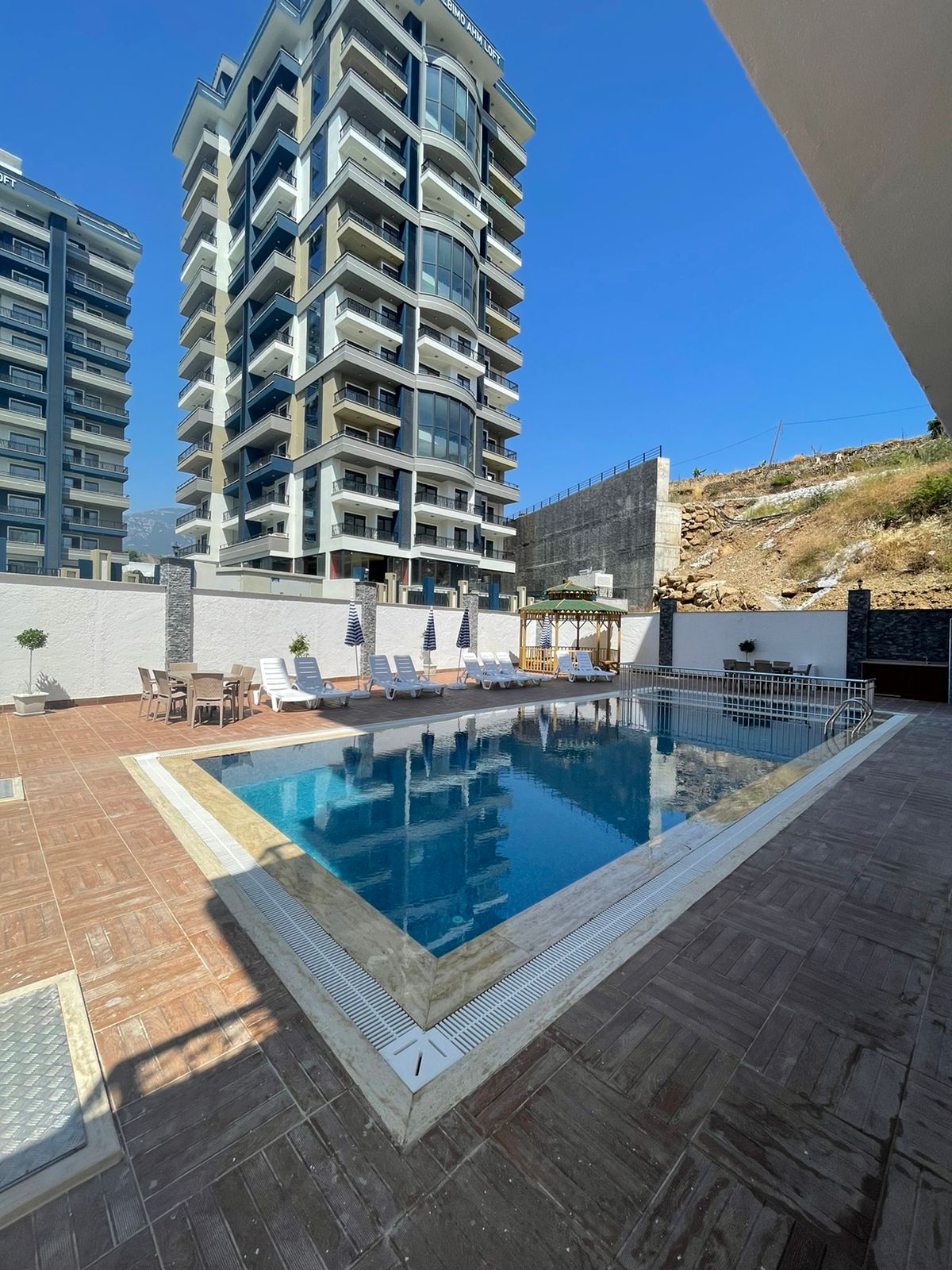 Outdoor pool beside a high-rise facade: a 2+1 penthouse for sale in Mahmutlar, Alanya, Turkey — New Level Group