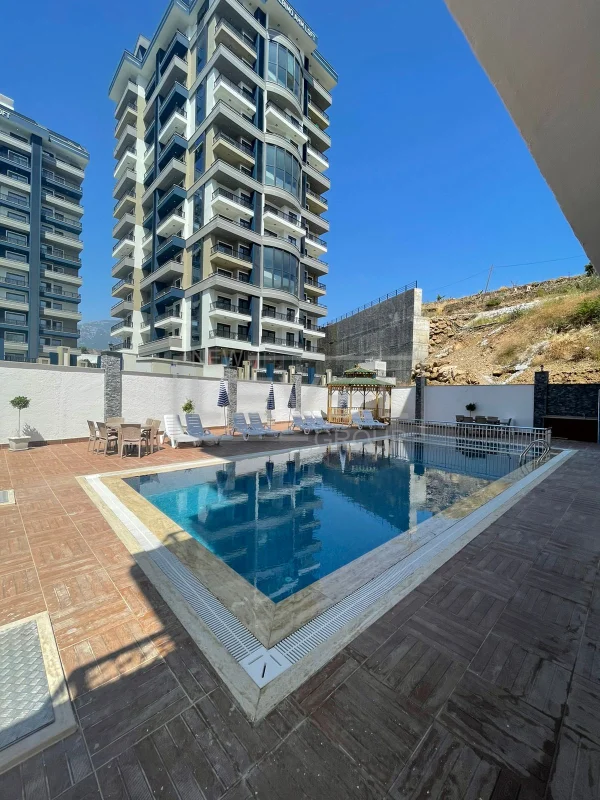 Yüksek balkonlu binanın önündeki açık havuz: Mahmutlar ilçesinde satılık 2+1 penthouse, Alanya, Türkiye — New Level Group