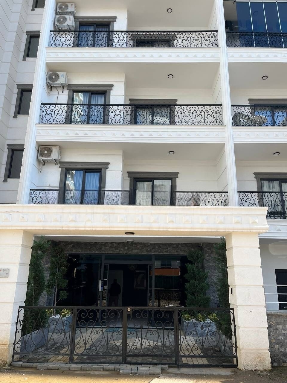 Light multi-storey facade with wrought-iron balconies and a canopied entrance in Alanya, Turkey