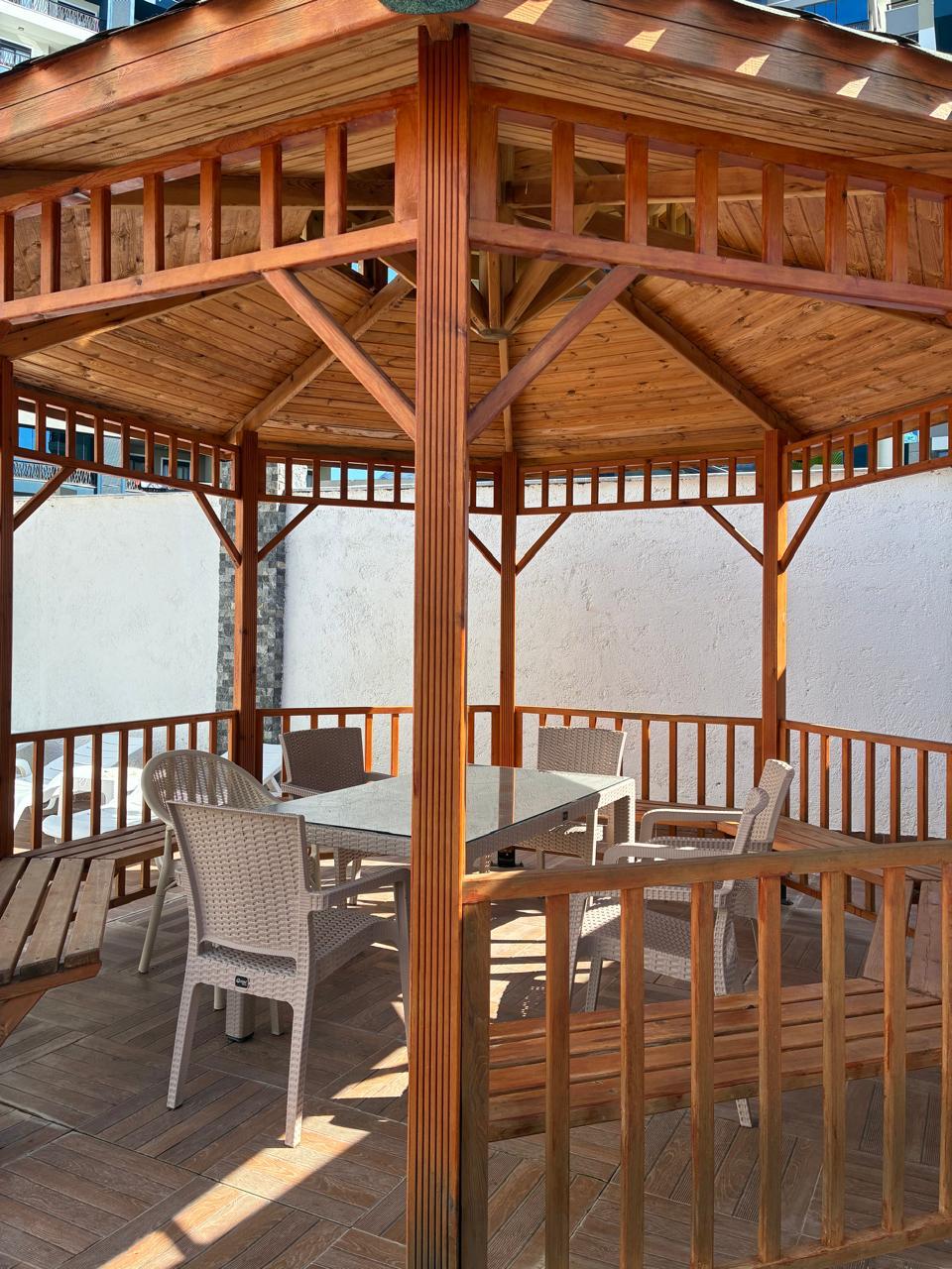 Wooden gazebo with wicker chairs and a glass-topped table on the grounds of a residence in Mahmutlar, Turkey