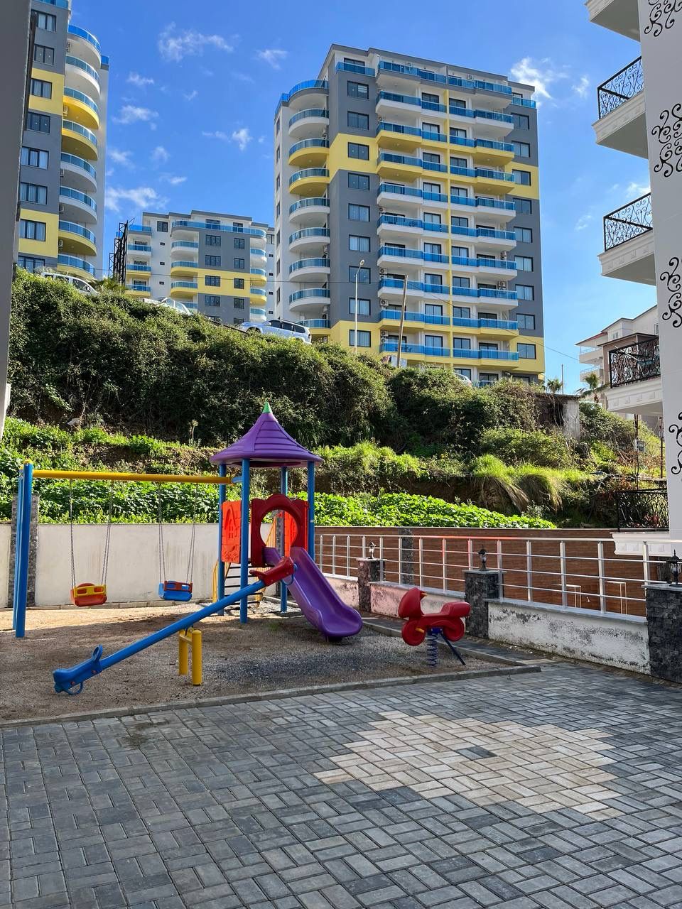 Outdoor children's playground with a purple slide and swings for residents of apartments in Alanya