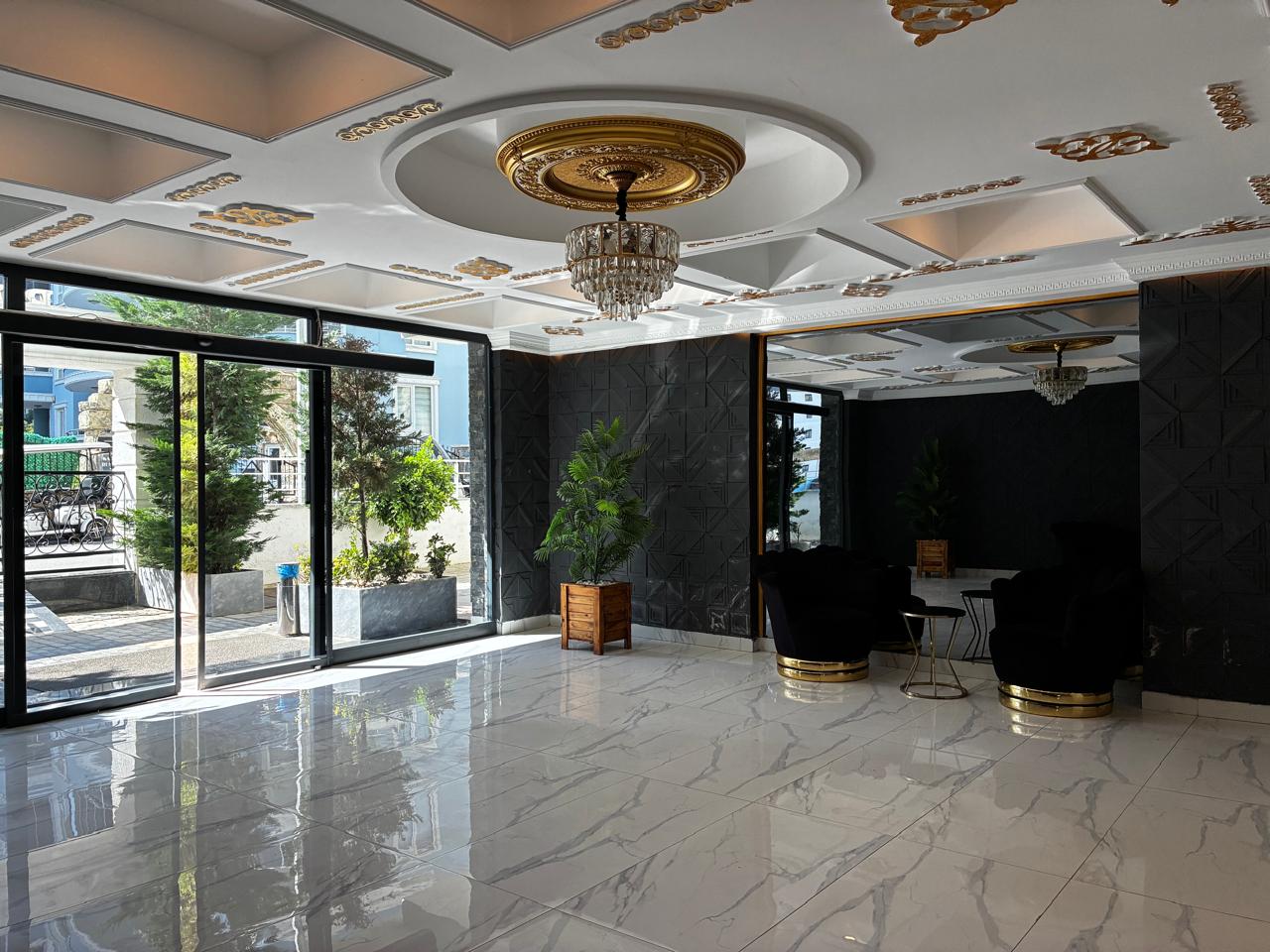 Lobby with panoramic glass doors, black columns and a crystal chandelier in a residence with apartments in Mahmutlar, Turkey