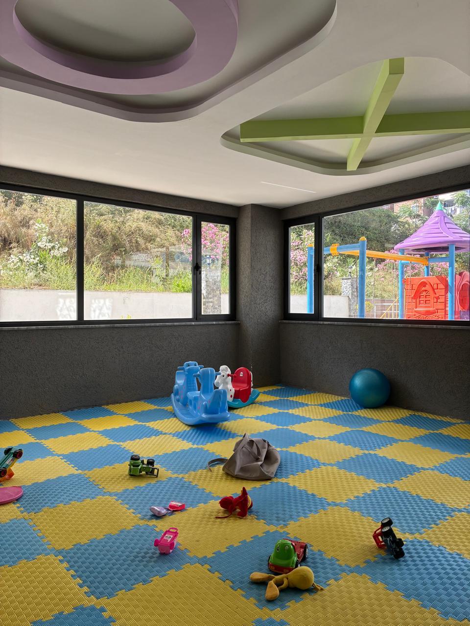 Indoor playroom with blue and yellow soft flooring and toys for residents of apartments in Alanya