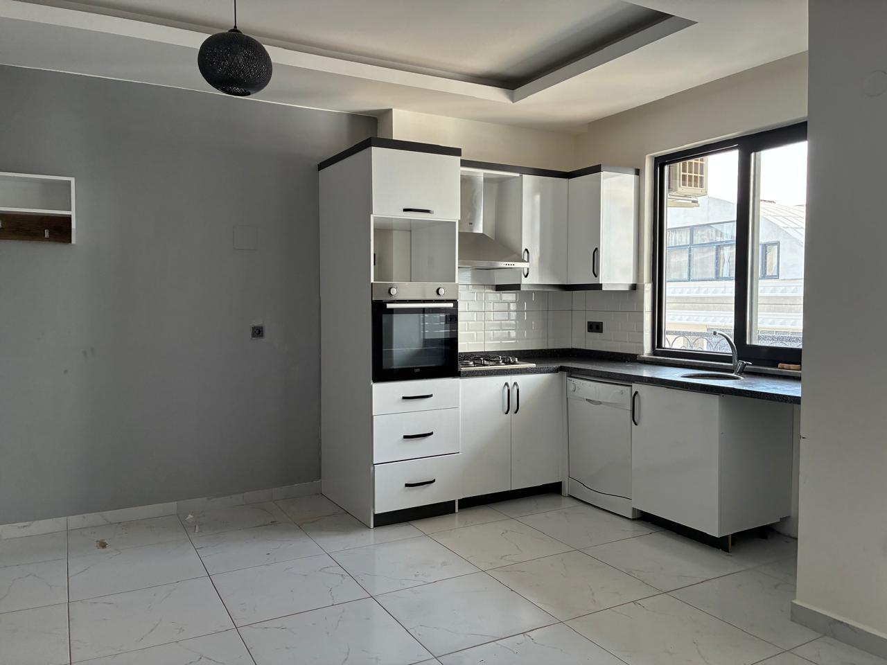 Kitchen-living room with a gas cooktop, steel extractor hood and wide black-framed window