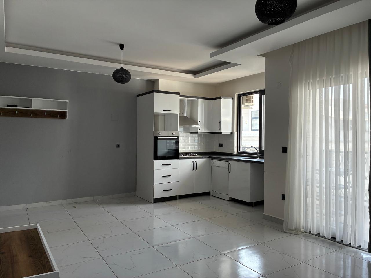 Kitchen-living room with a grey accent wall and marble-look tile in Alanya where the home is for sale