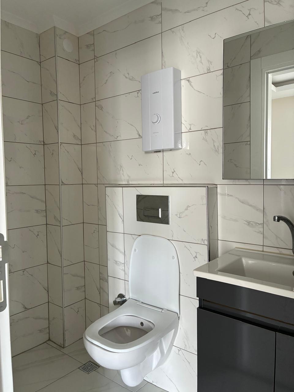 Bathroom with a wall-hung toilet, mirrored cabinet and tall black faucet in a residence