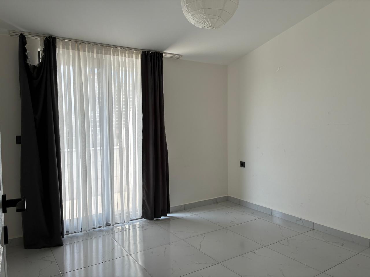 Empty bedroom with a panoramic balcony door and dark blackout curtains in Mahmutlar