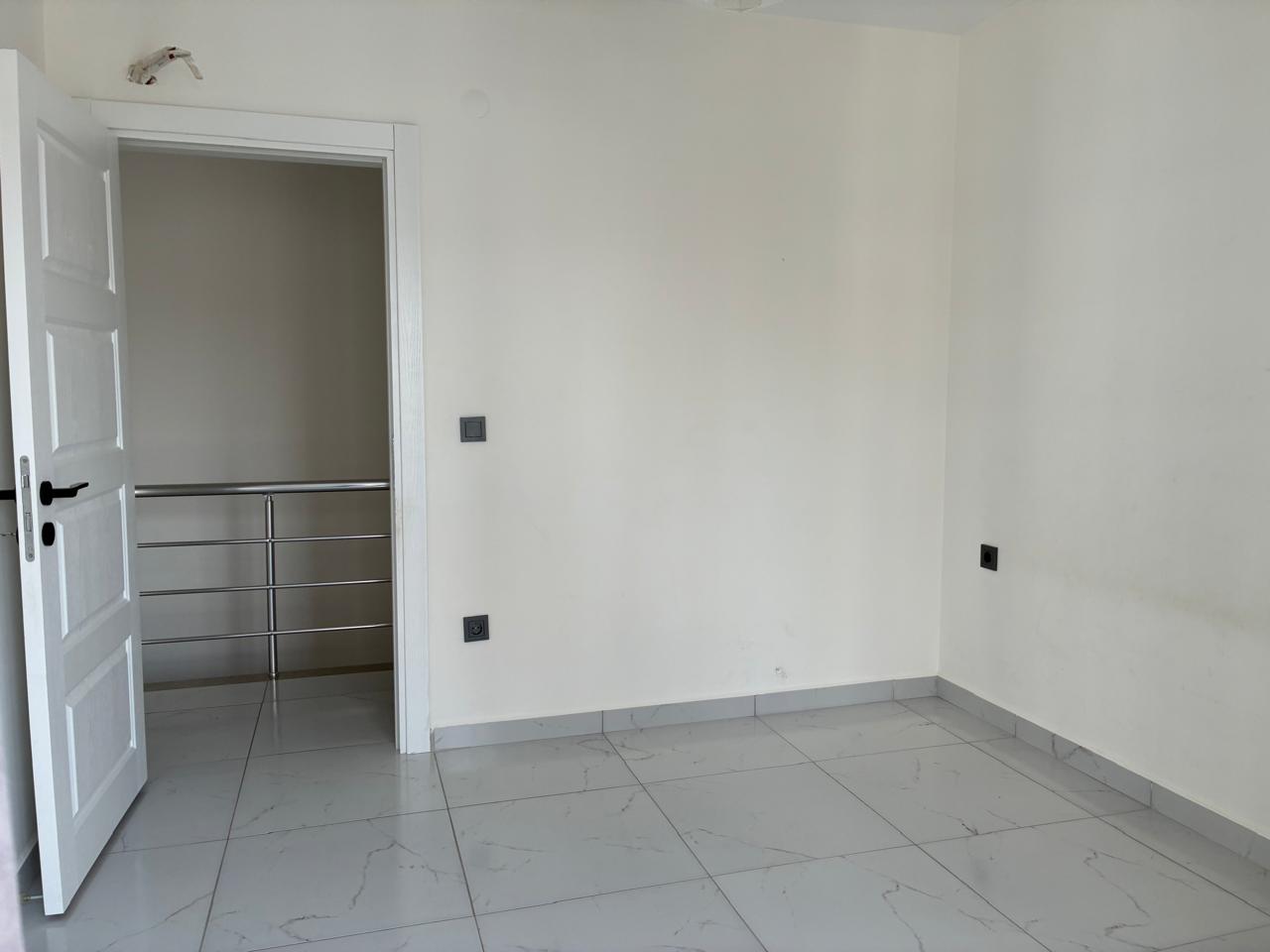 Bedroom with white walls, an open door and stair railing in a penthouse