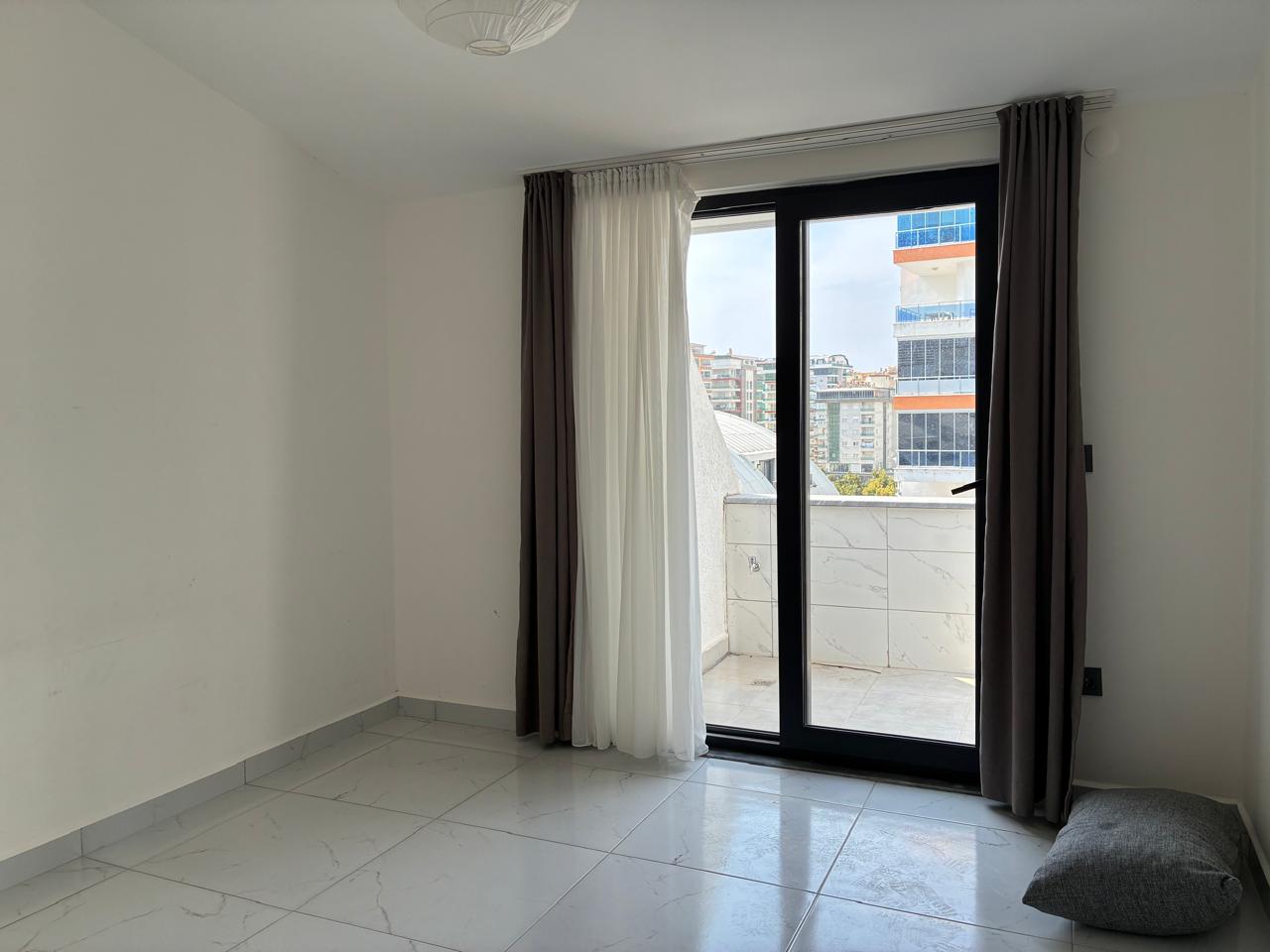 Bedroom with a black-framed balcony door, grey curtains and light marble-look porcelain flooring