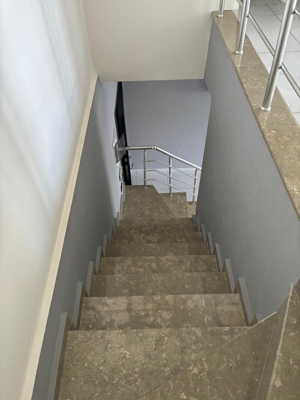 Grey stone stair flight with metal railings and a turn toward the lower level