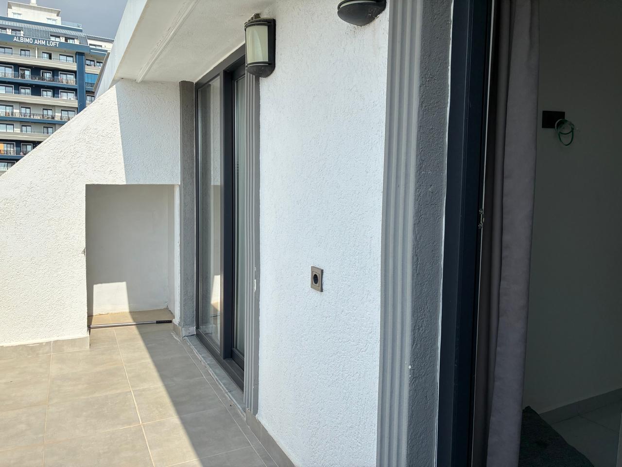 Open terrace with grey tiles and panoramic glazing in a top-floor apartment in Turkey