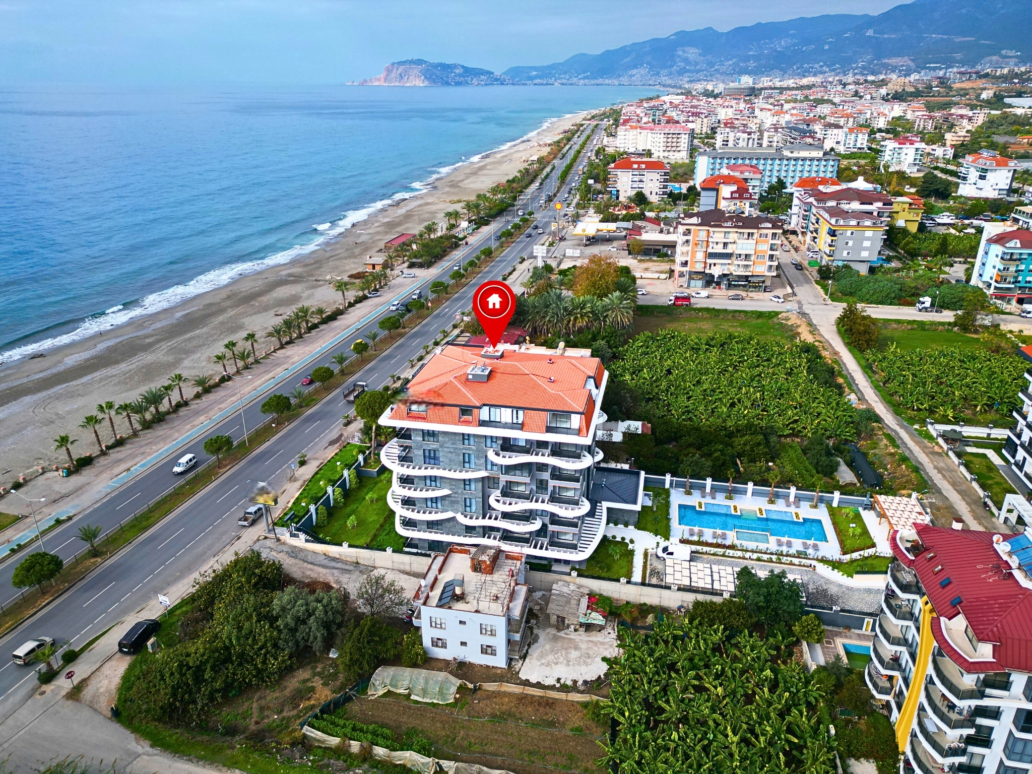 Aerial view of the pool complex beside a sandy beach in Turkey, where apartments are for sale