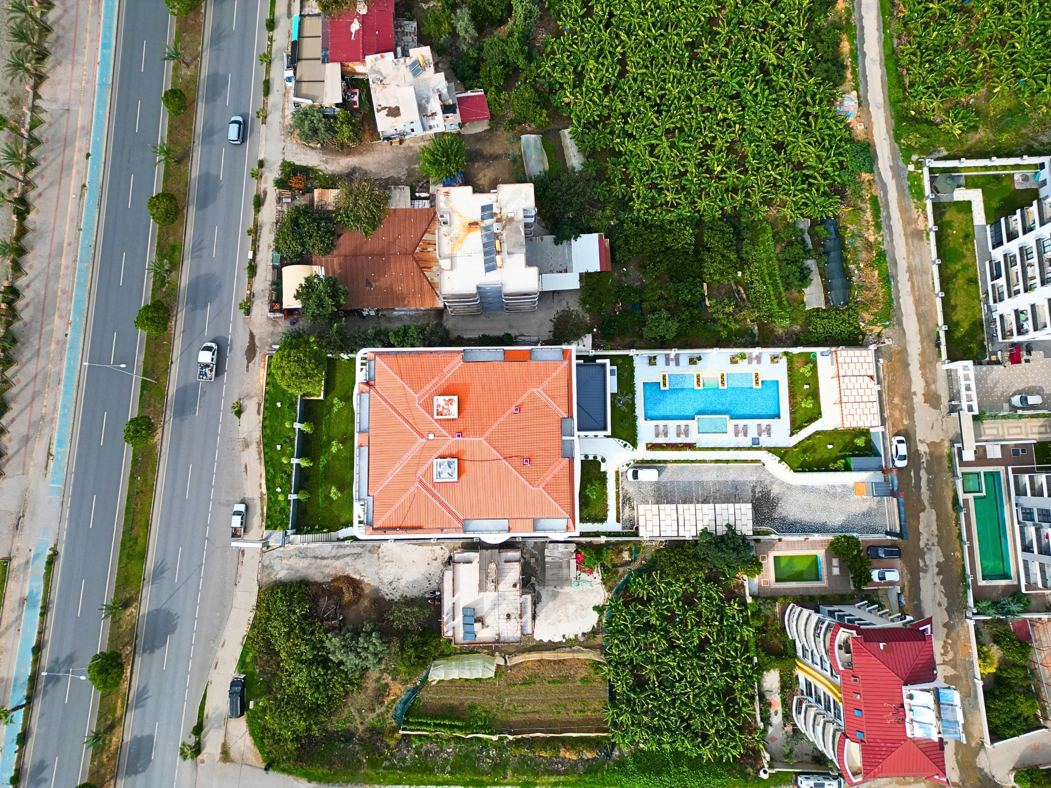 Outdoor pool with loungers beside the red-tiled roof building near the sea