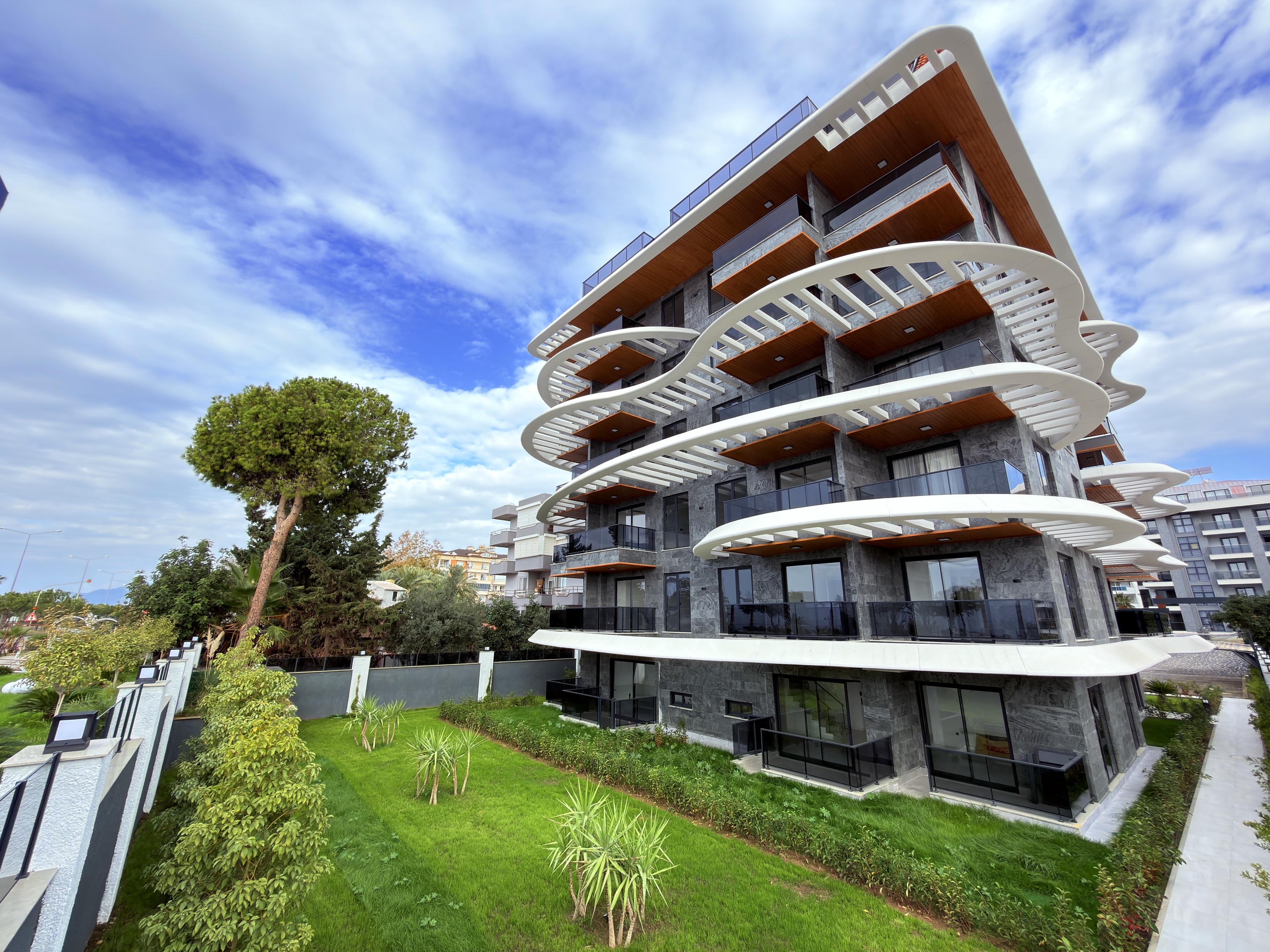 Gray stone facade with white wave-shaped balconies at a residence for sale in Alanya