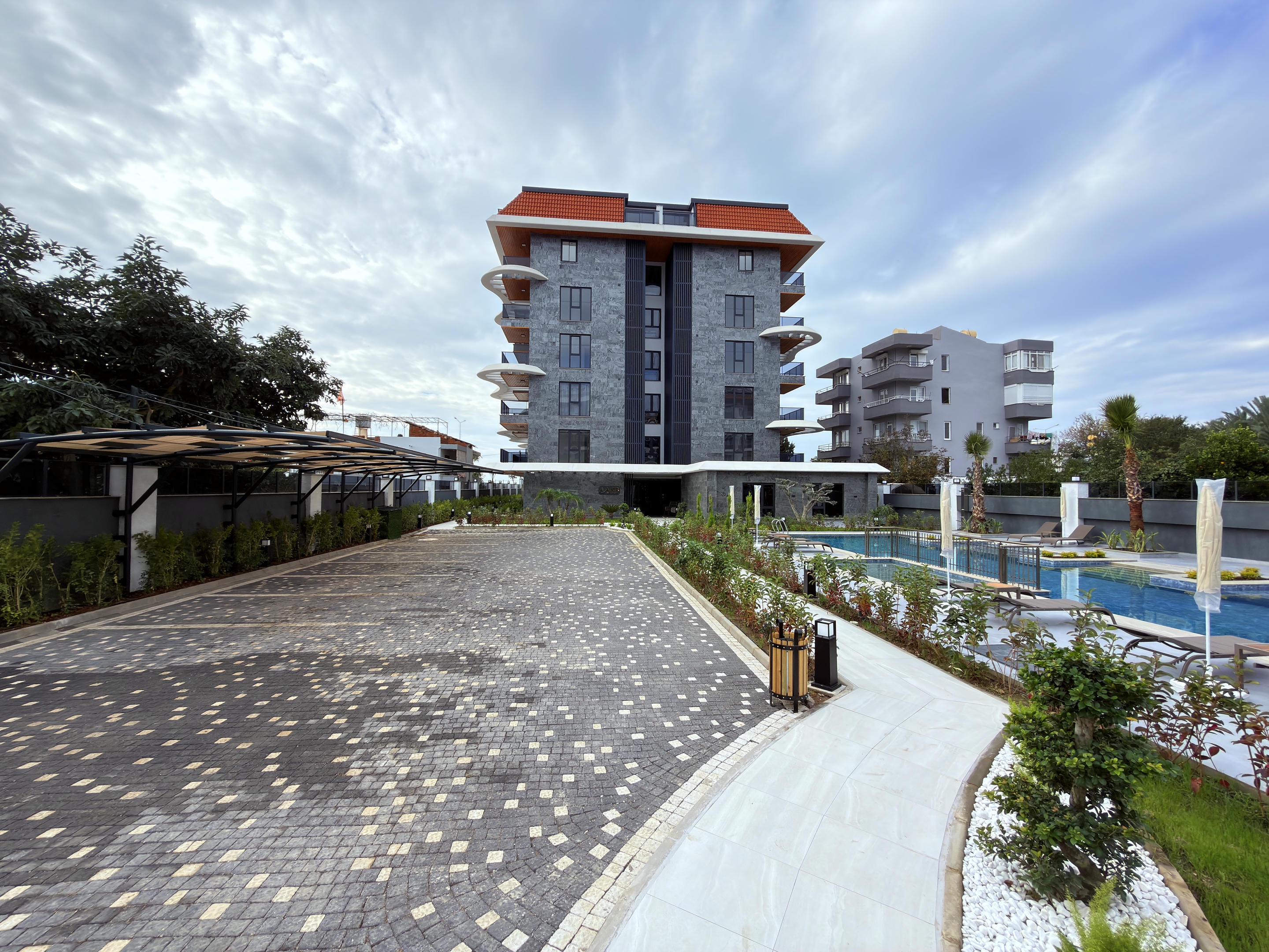 Five-story stone facade with rounded balconies and a pool for apartments in Turkey
