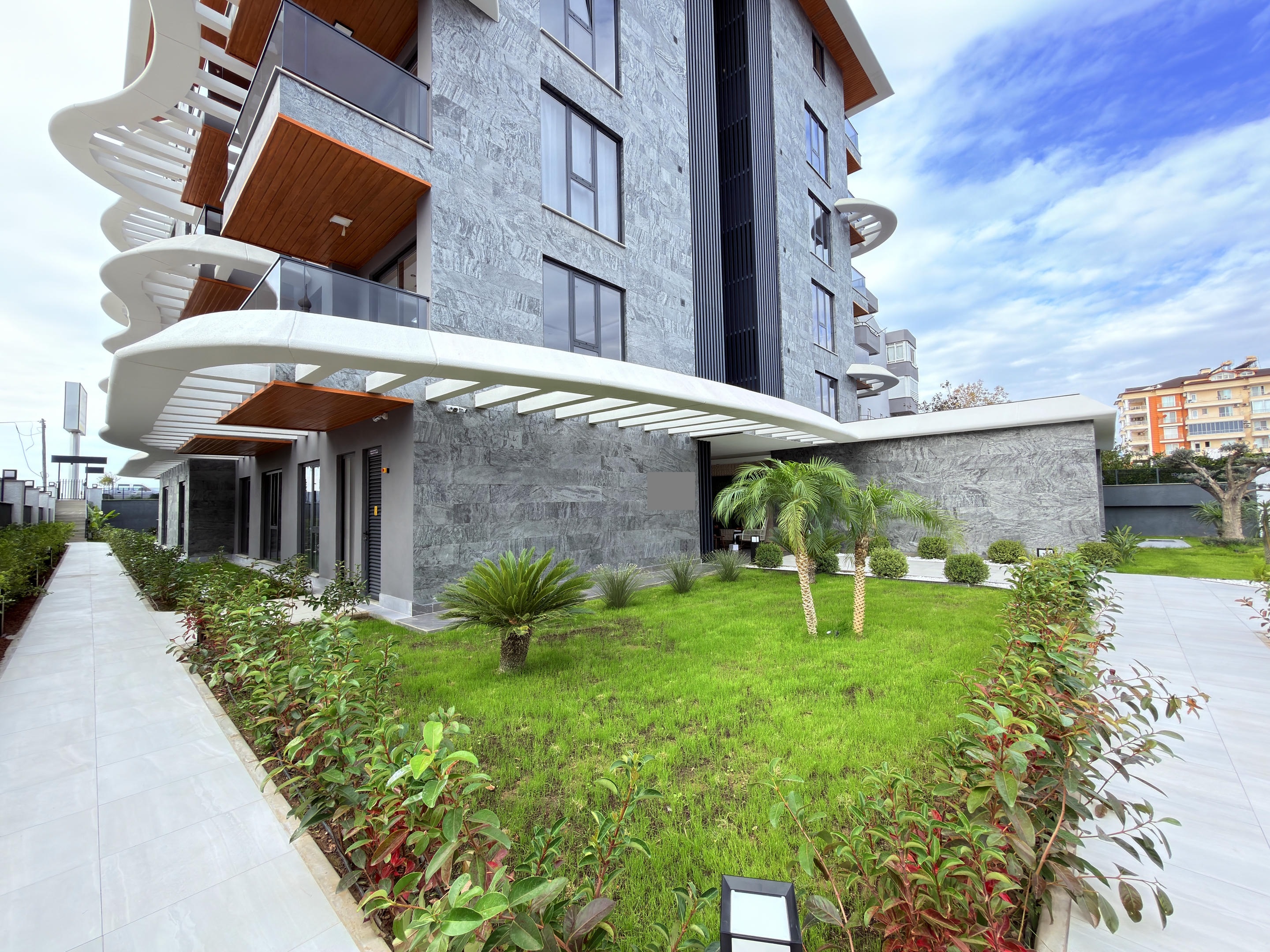 Entrance beneath a white canopy with rounded balconies at a residence
