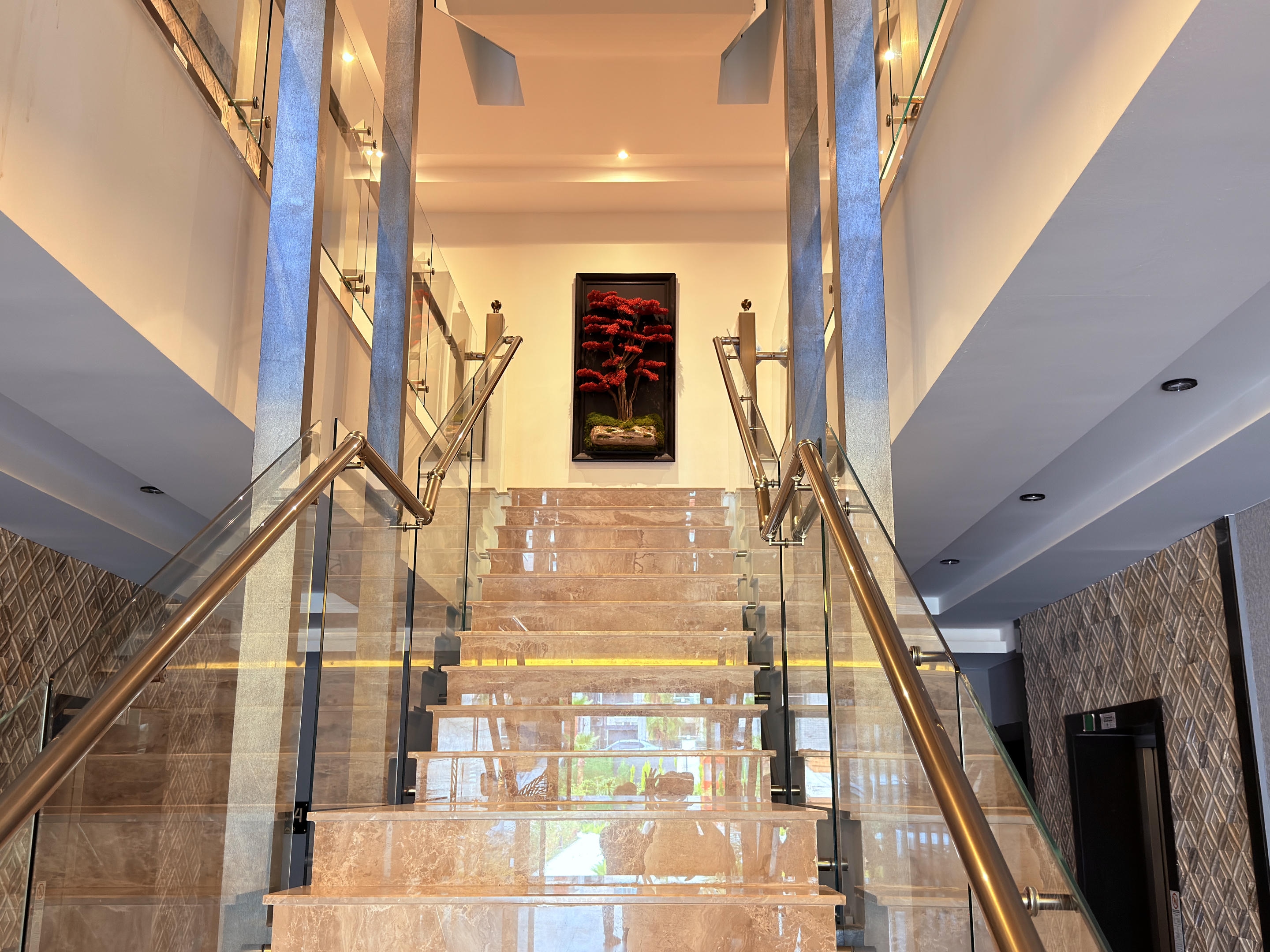 Stair hall with a wide beige stone staircase, mirrored panels and illuminated steps