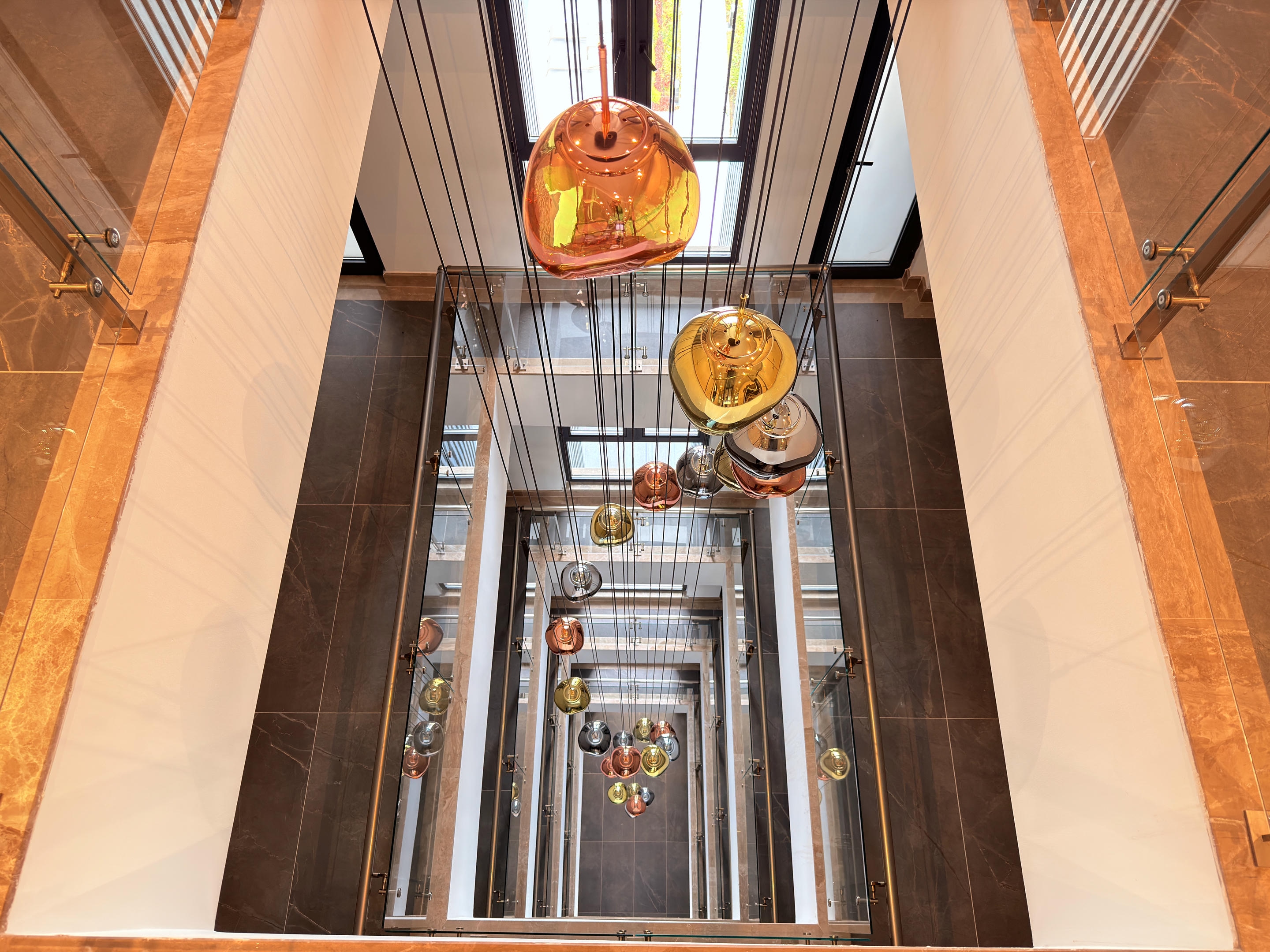 Tall stair hall with an amber pendant light and marble edges in a complex with apartments in Alanya