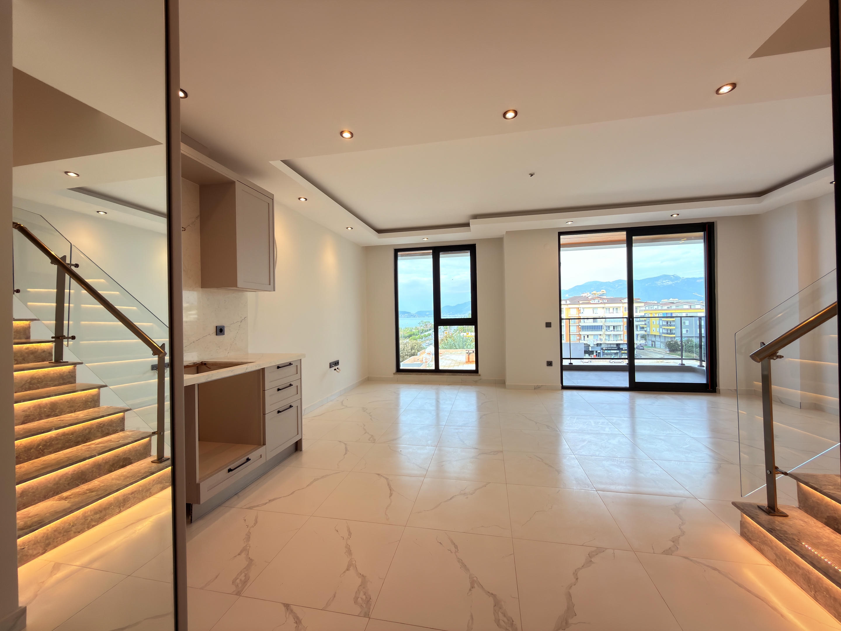 Kitchen-living room with a light kitchen, illuminated staircase and city and mountain views at a duplex