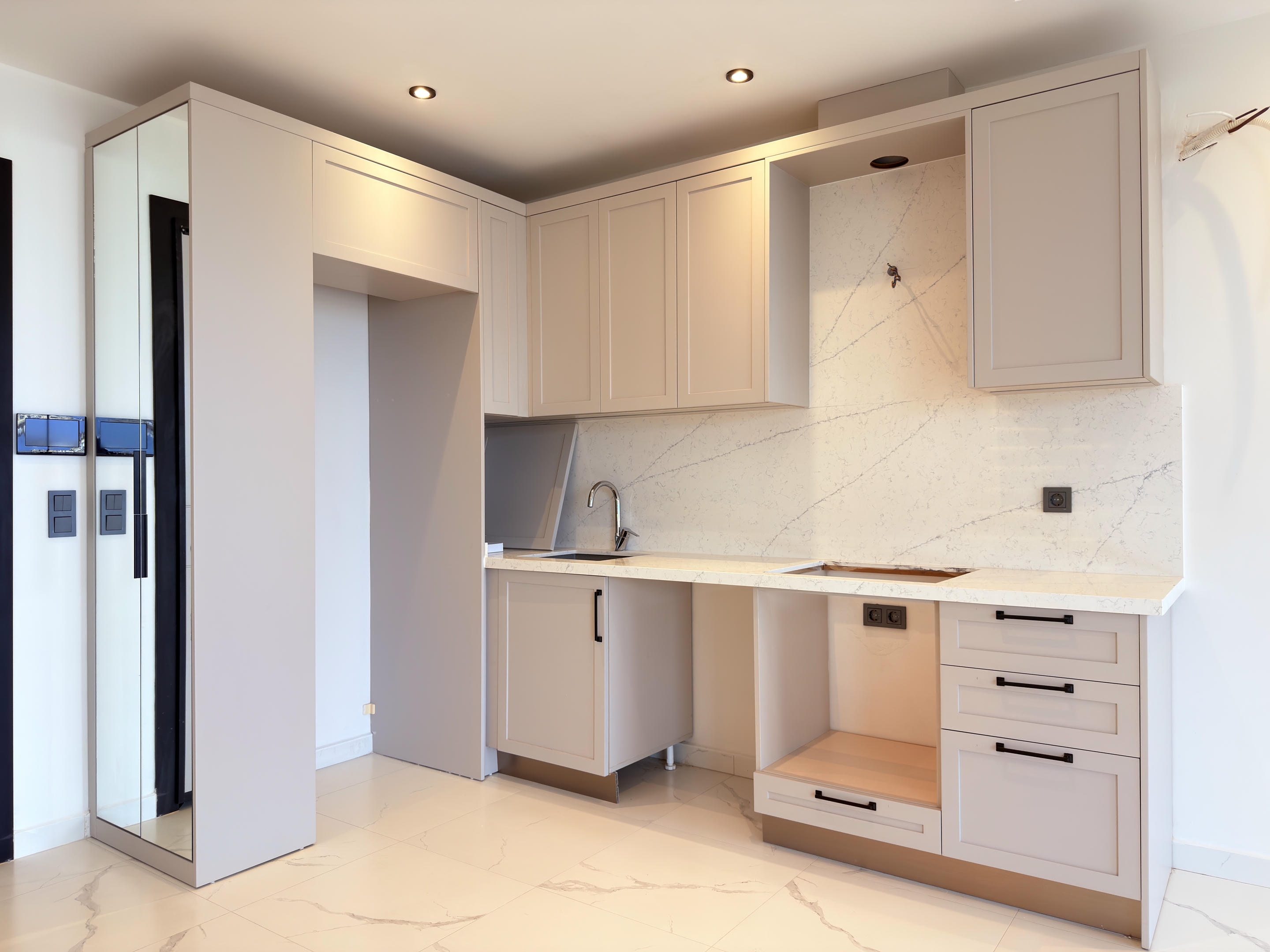 Kitchen with light corner cabinetry, tall cupboards and marble-look backsplash in apartments in Alanya
