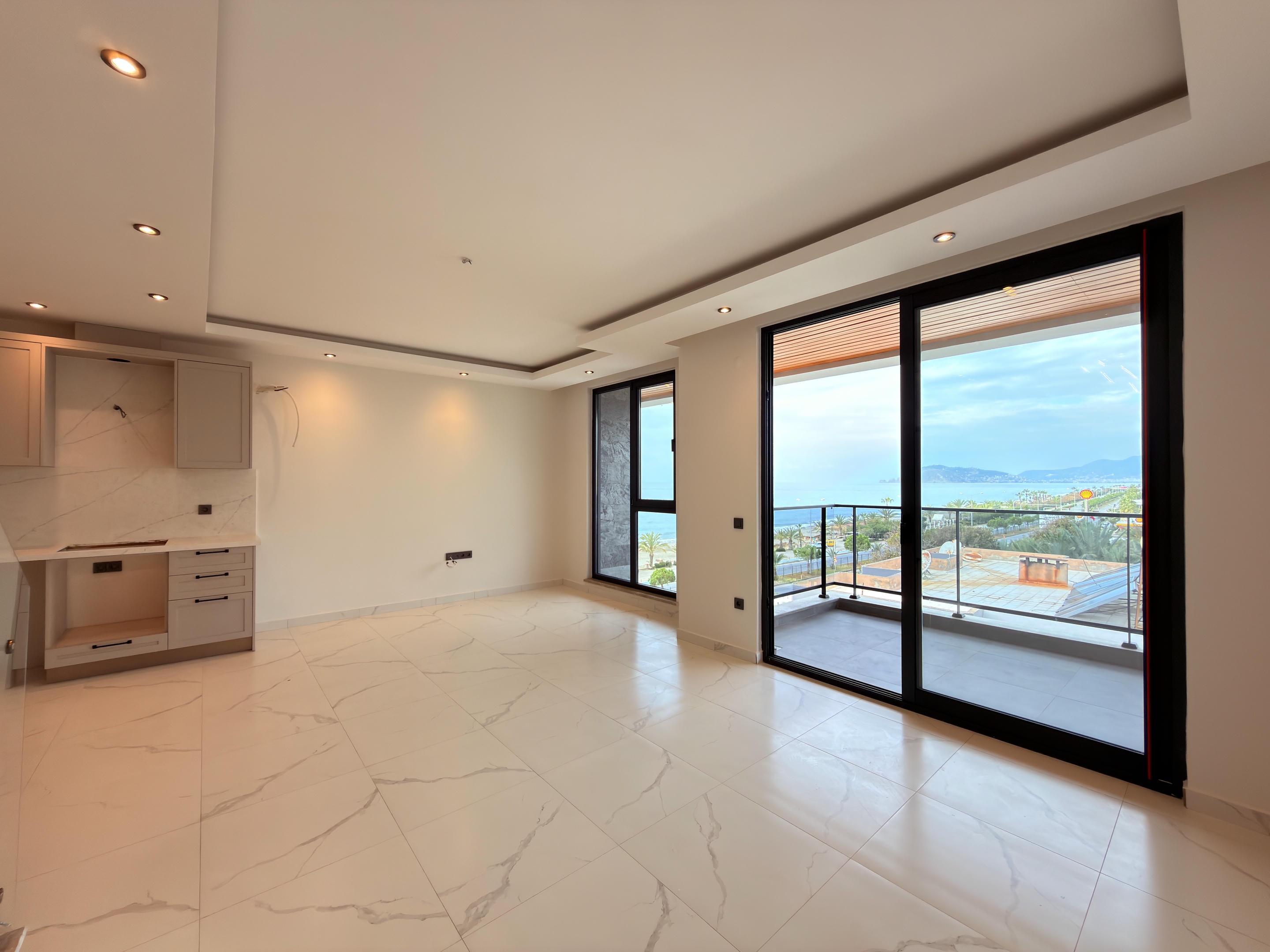 Kitchen-living room with panoramic sliding doors to a sea-view balcony where homes are for sale