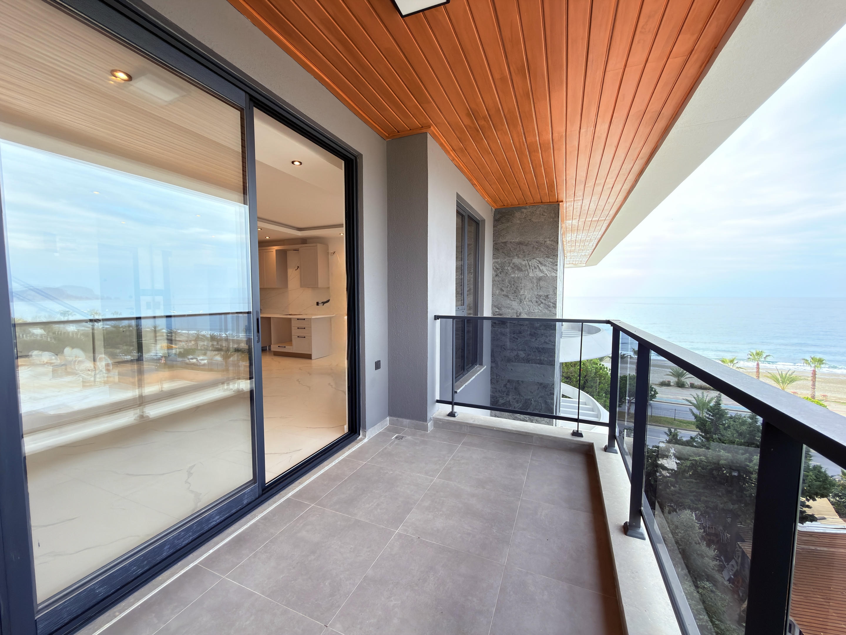 Narrow balcony with panoramic door, sea view and coastal palms at a penthouse for sale