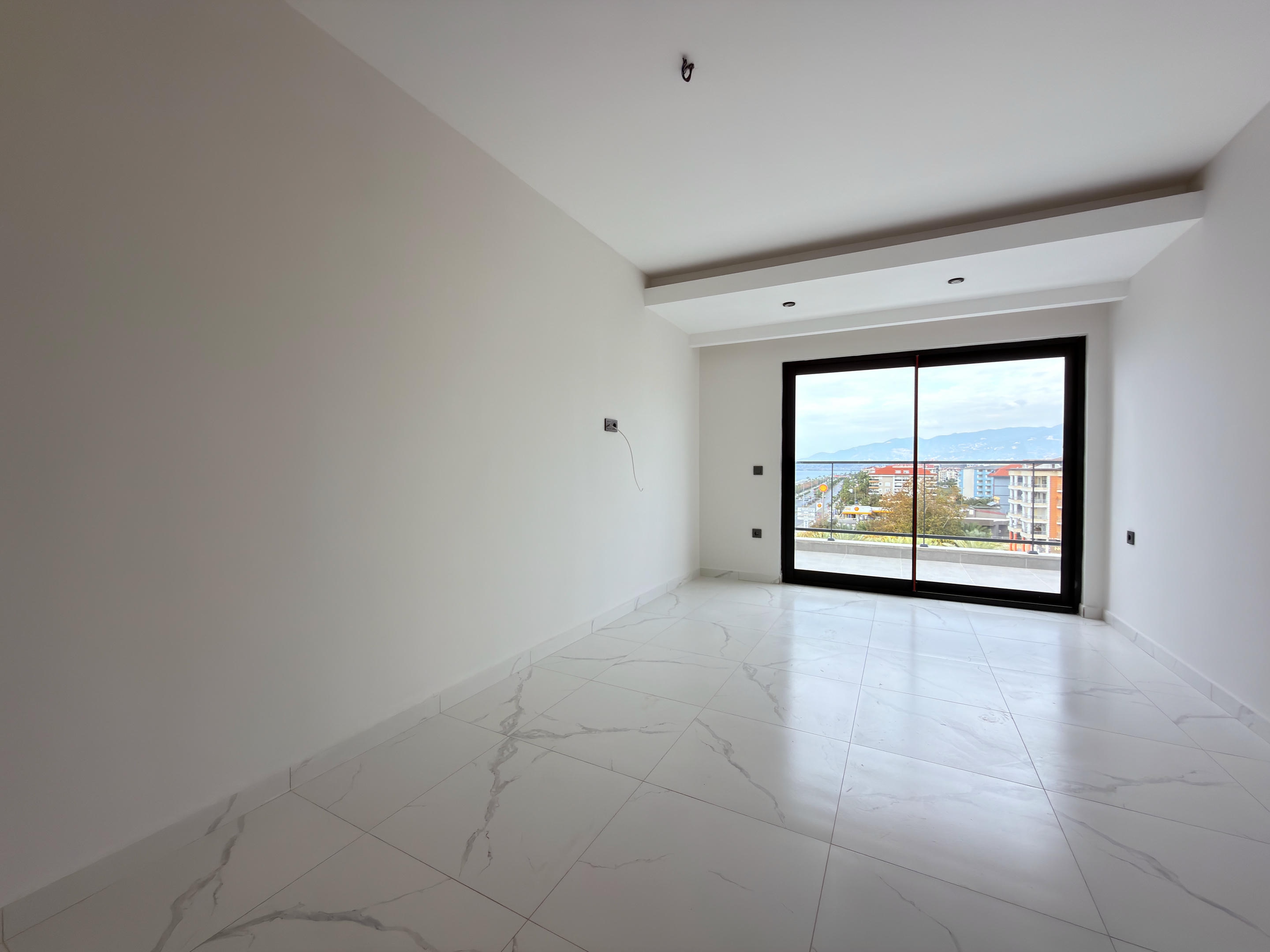 Empty kitchen-living room in a home for sale in Turkey with a balcony door and mountain views