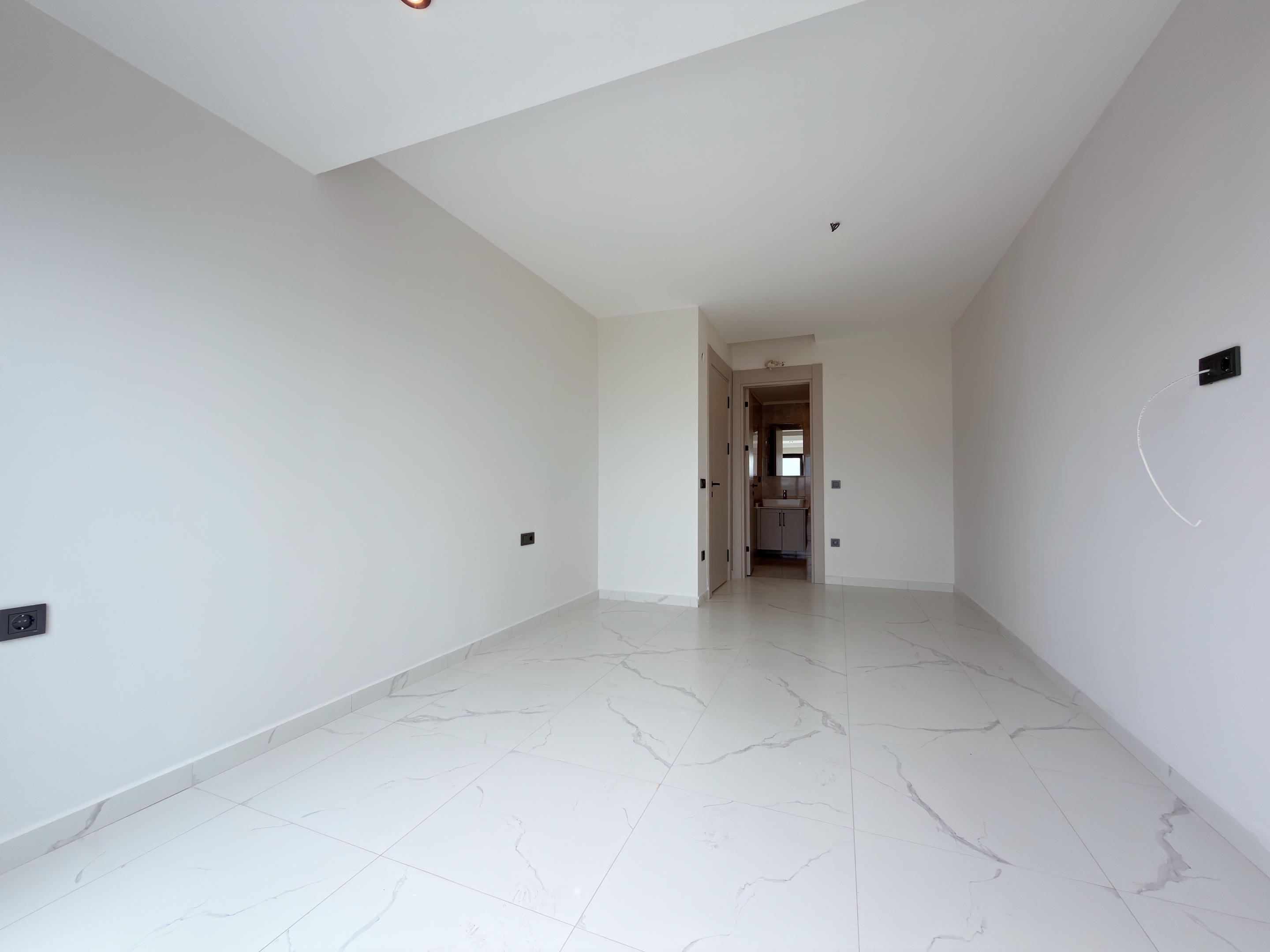 Long kitchen-living room with utility connections and a hall opening at a residence for sale