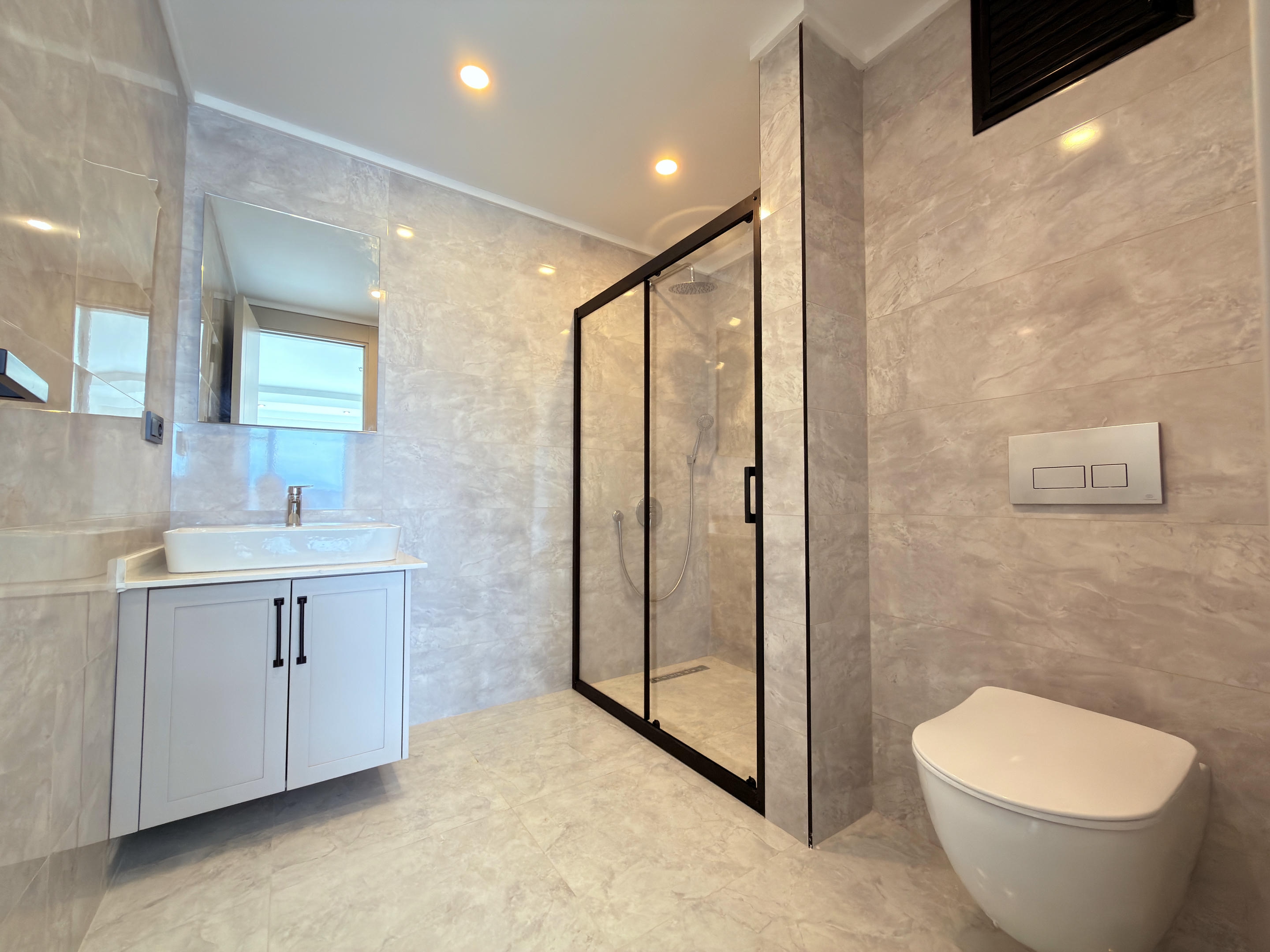 Bathroom with a glass shower enclosure, vessel sink and wall-hung toilet