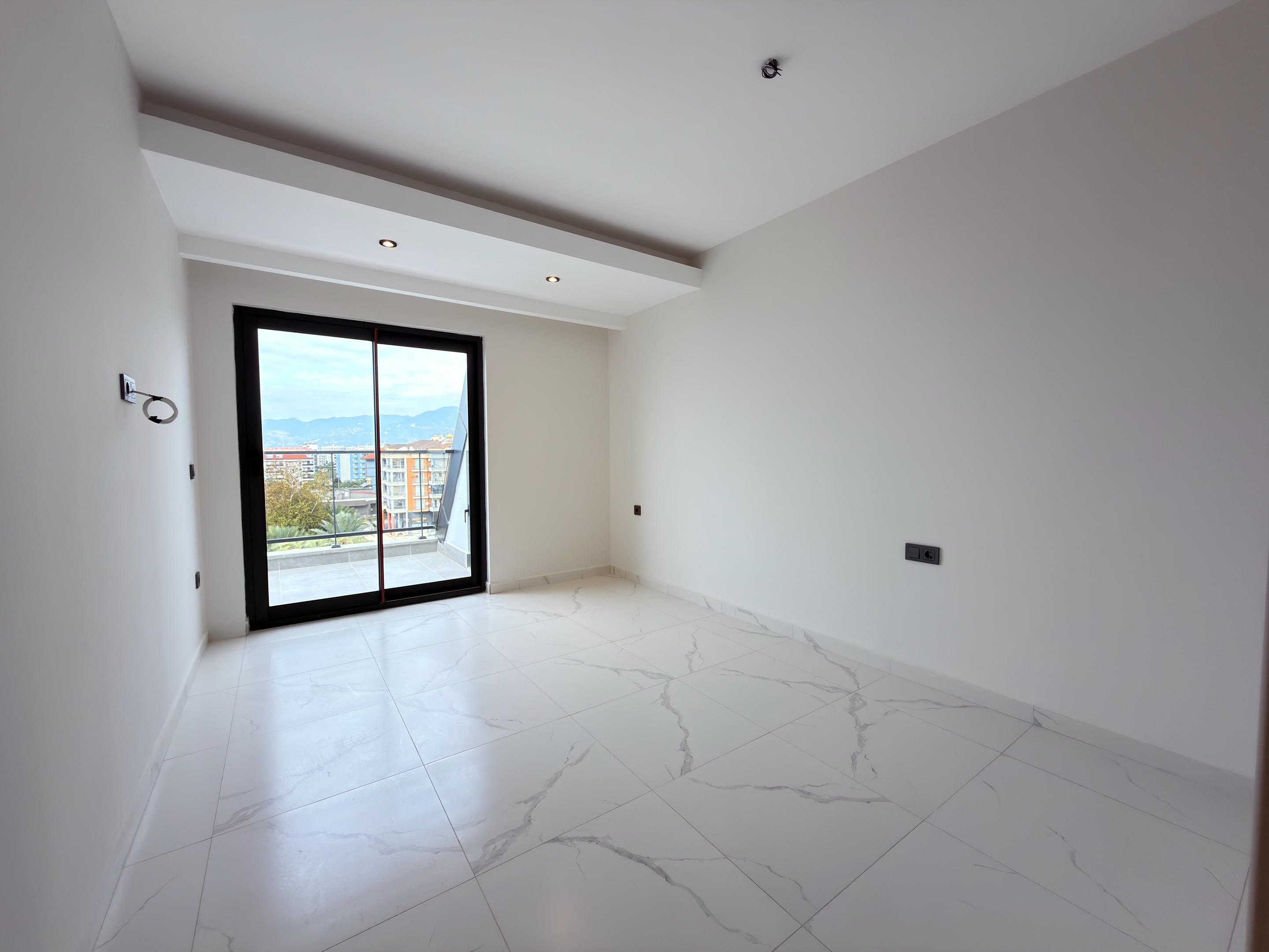 Bright bedroom with balcony access and distant mountain views at a penthouse