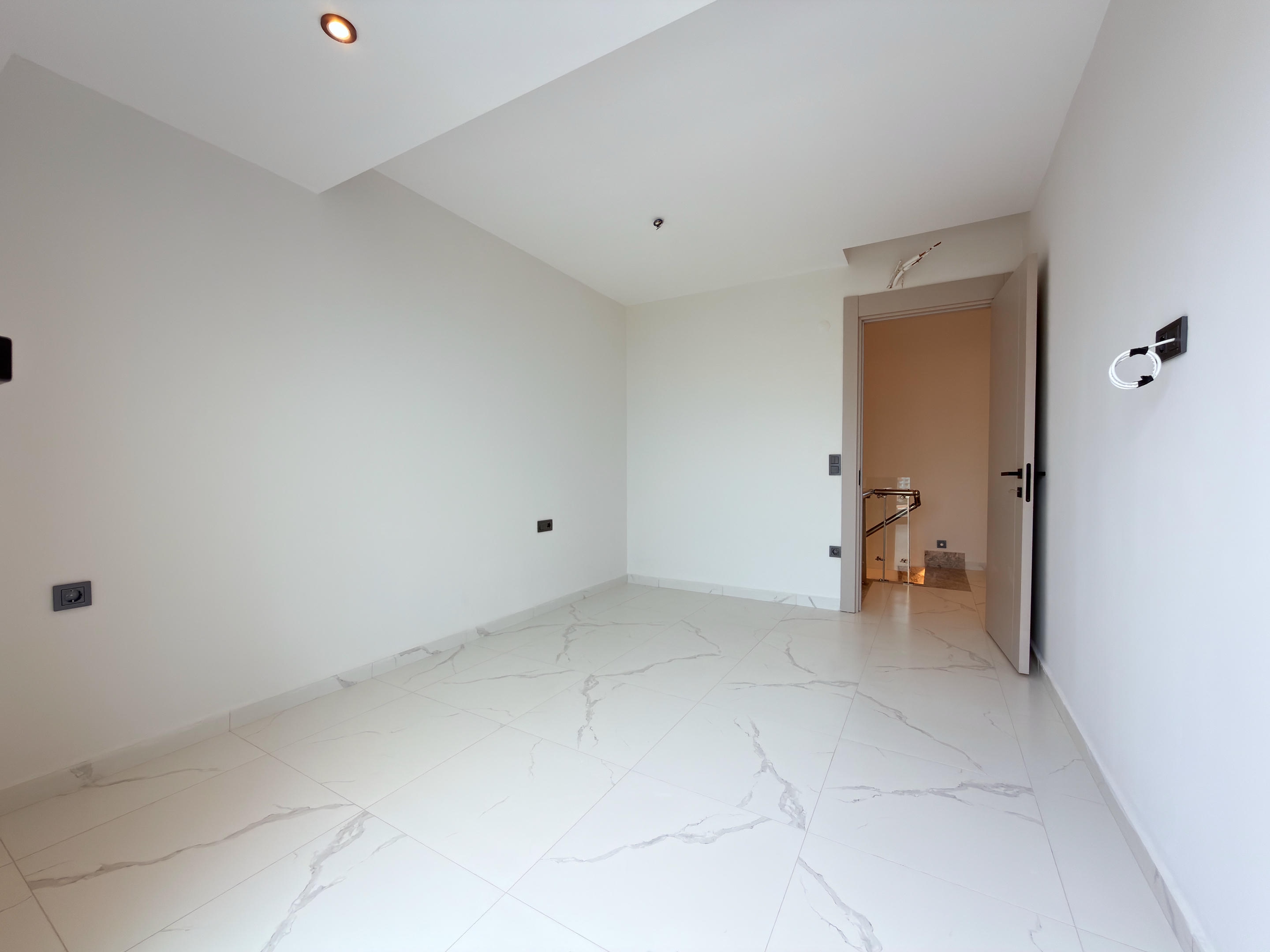 Empty bedroom with a light floor and open doorway to the stair hall in Alanya