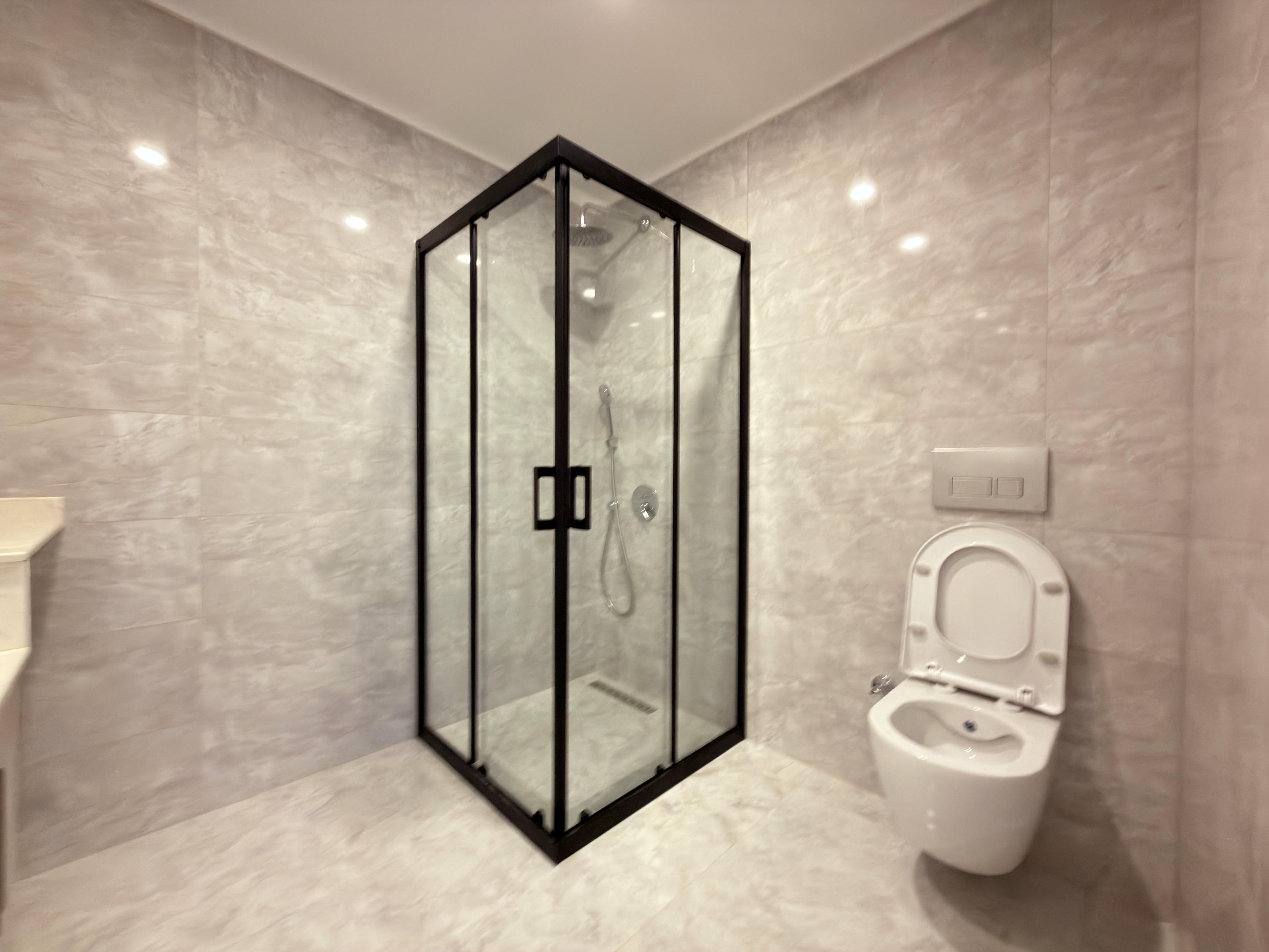 Bathroom with a corner shower enclosure and rain shower head in apartments in Kestel