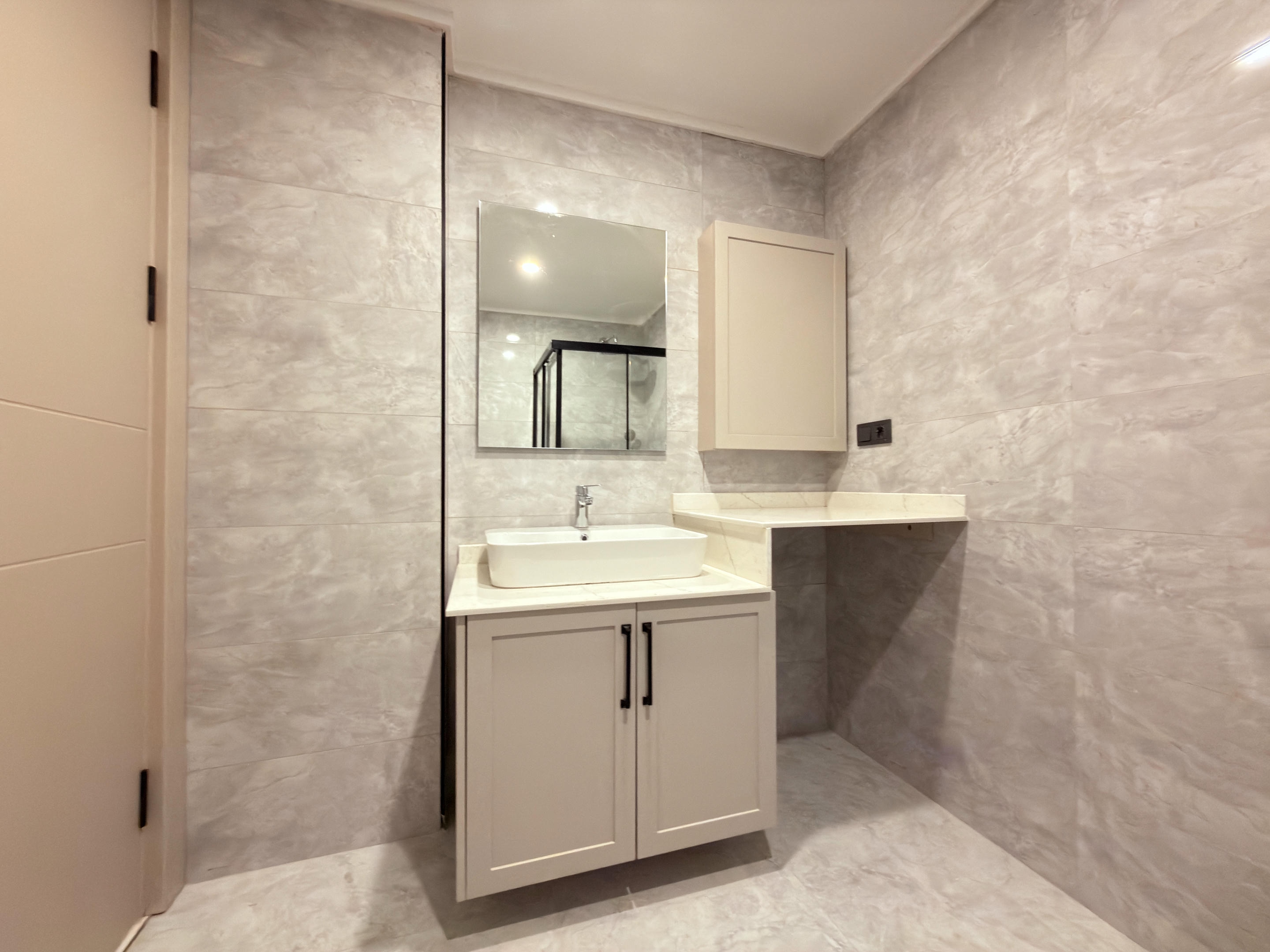 Bathroom with a vessel sink, long white countertop and mirror above the vanity