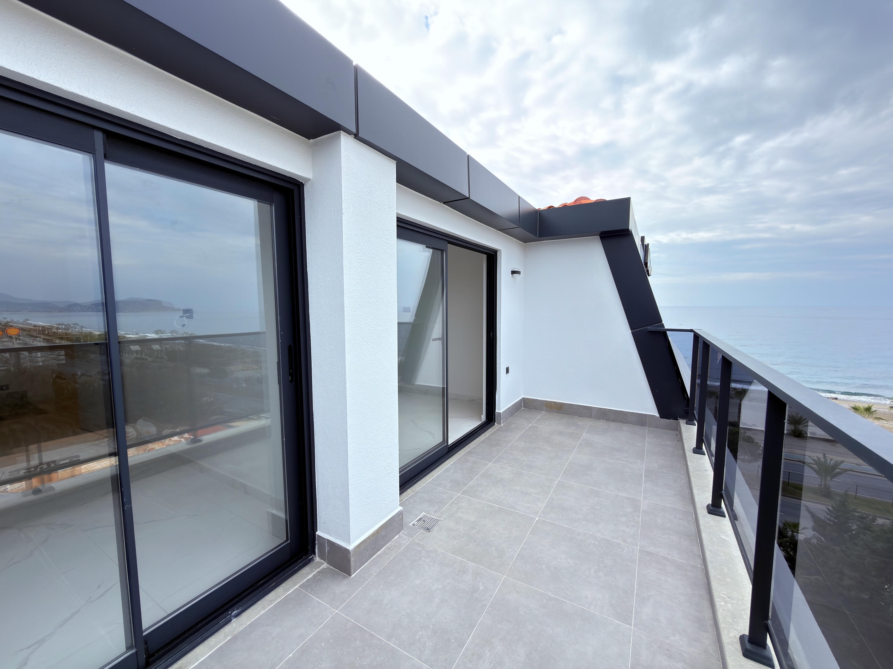 Narrow balcony with panoramic sliding doors and a side sea view at a duplex in Turkey