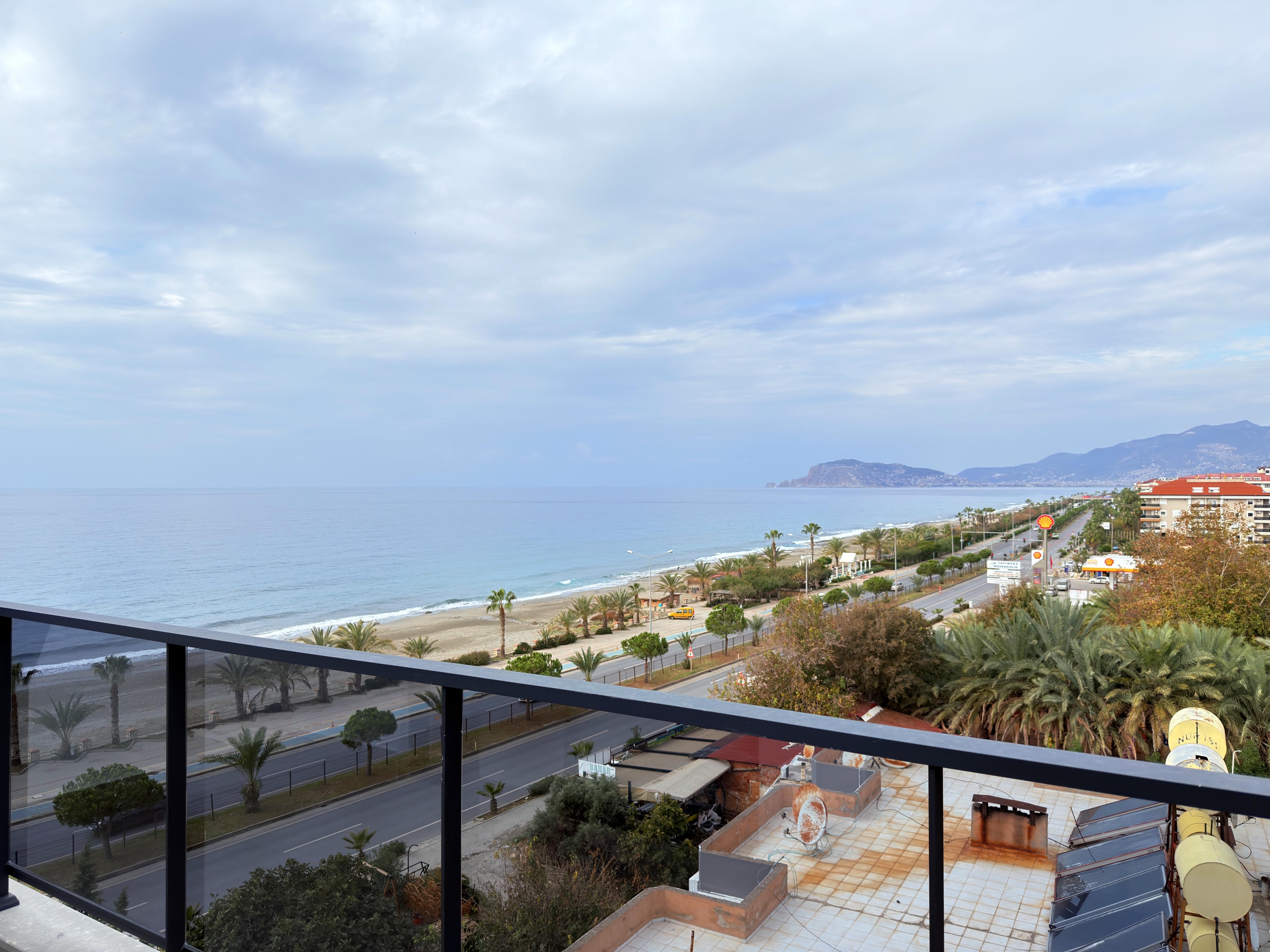 Sea view from a balcony above the sandy beach, palm promenade and coastal road near the sea