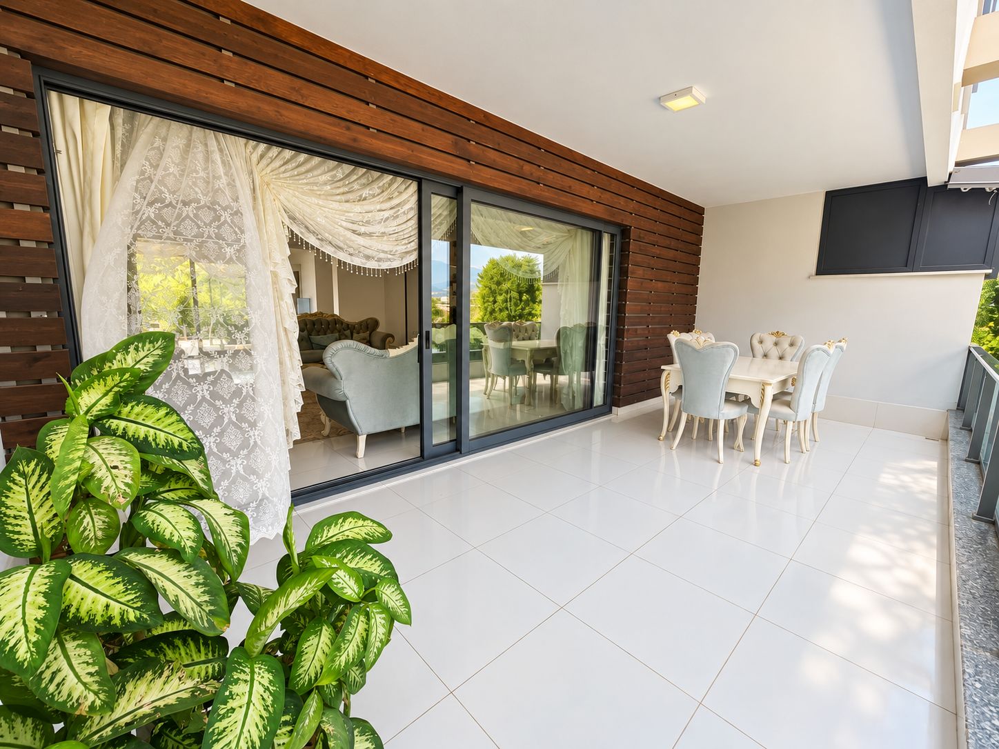 Covered terrace with a dining table, wood slat wall finish and potted plant at an apartment in Kargicak