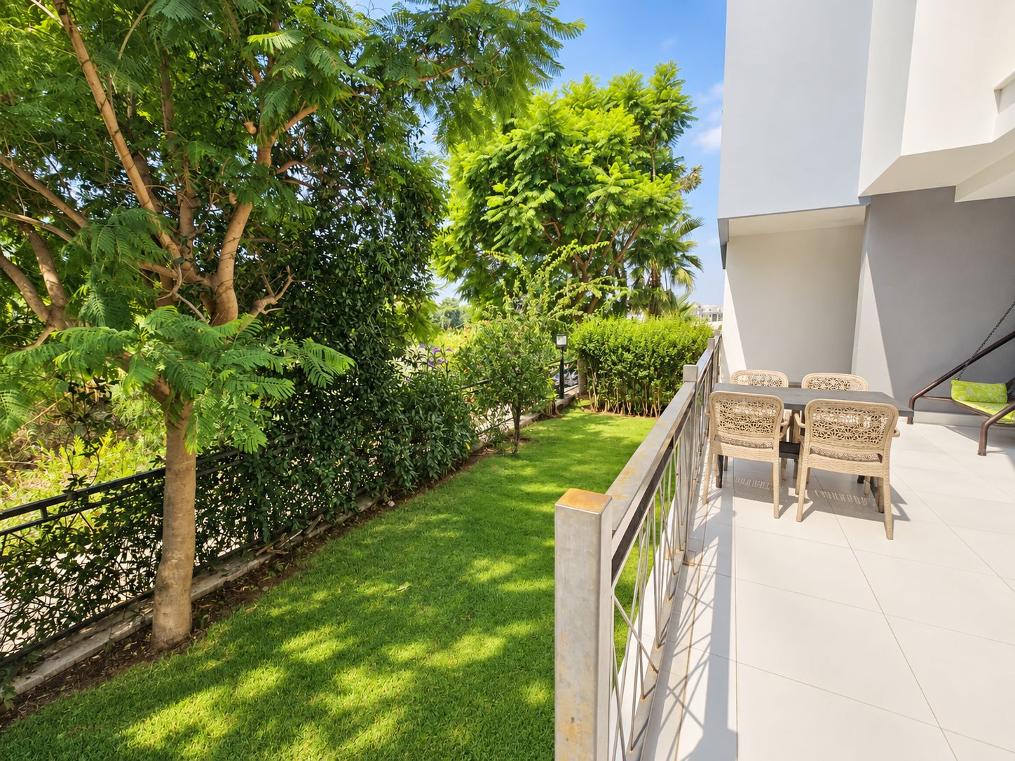 Open terrace with wicker chairs, a lawn and tall leafy trees beside the building in Turkey