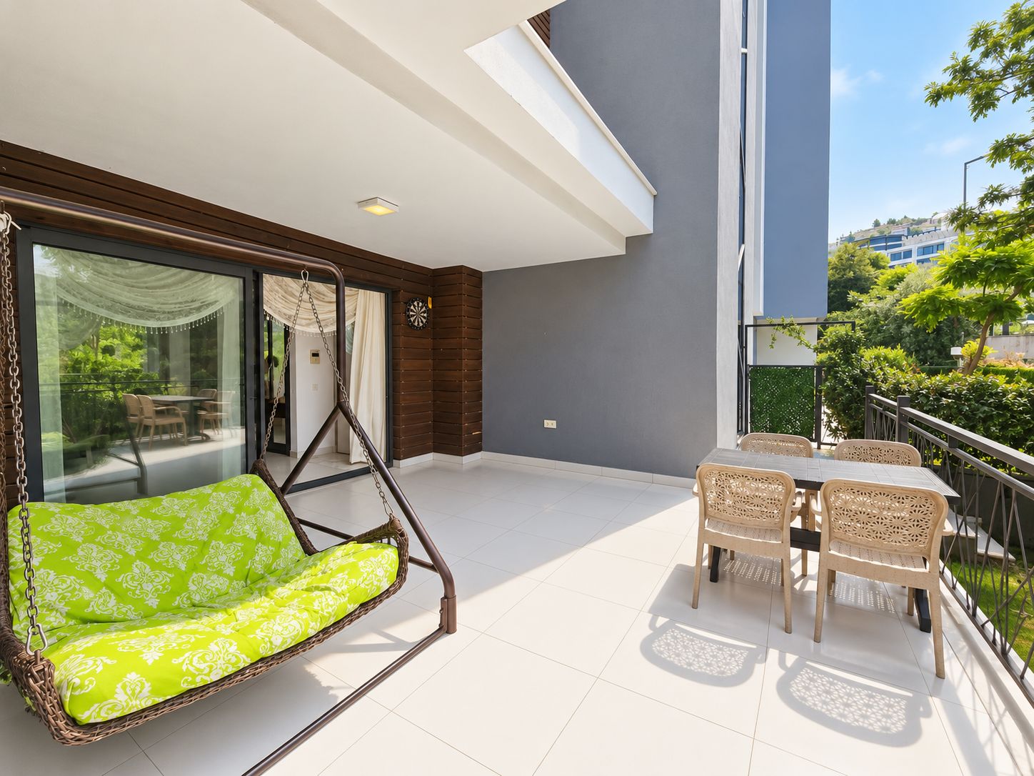 Terrace with a hanging swing, wicker dining chairs and tree views at a 2+1 home for sale
