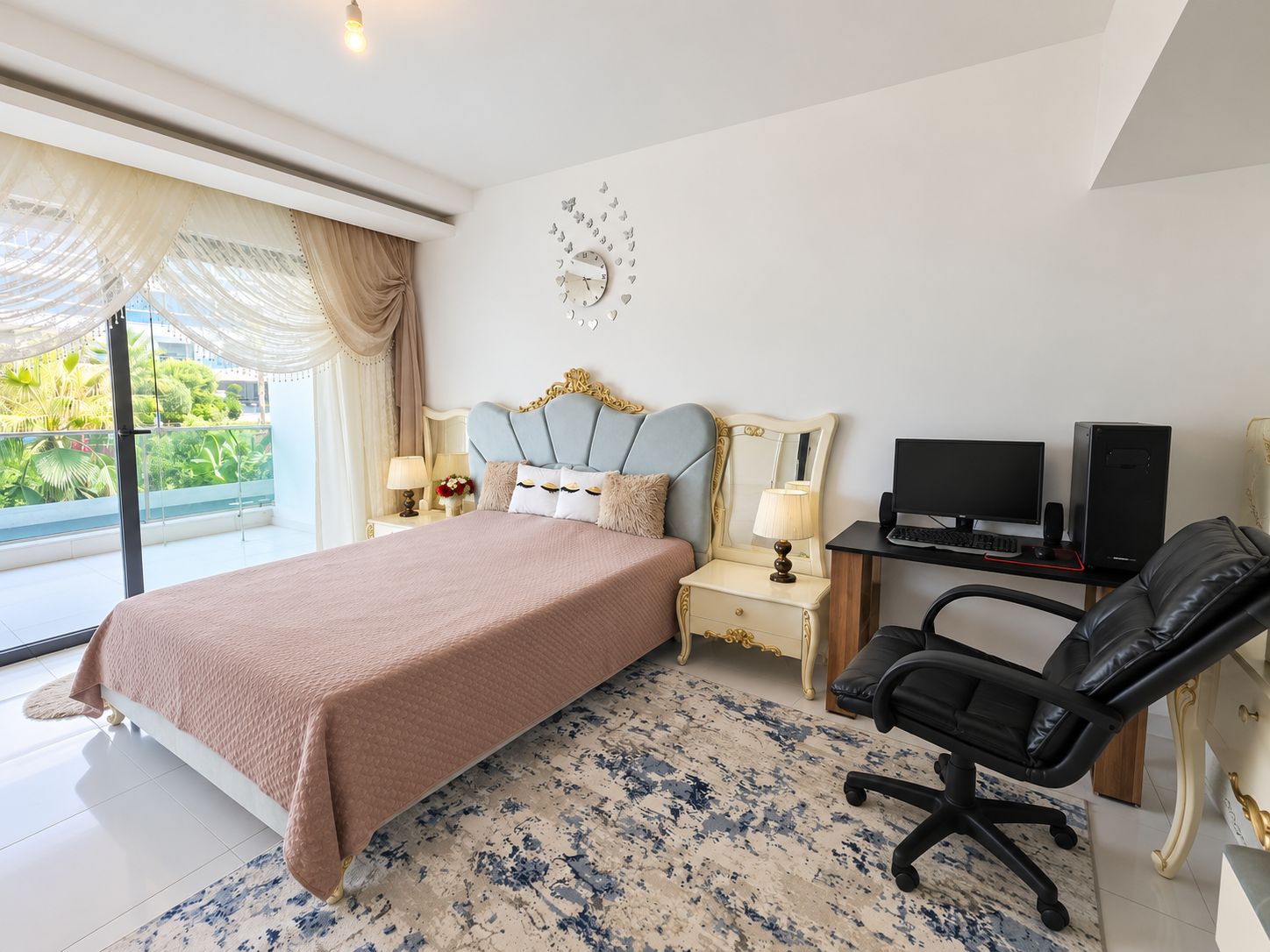 Bedroom with a pink-covered double bed, blue headboard and desk in an apartment