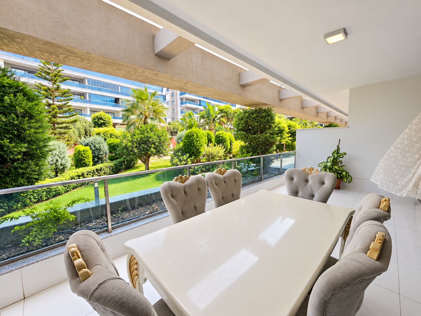 Terrace offered for sale with a white dining table, six upholstered chairs and glass railing