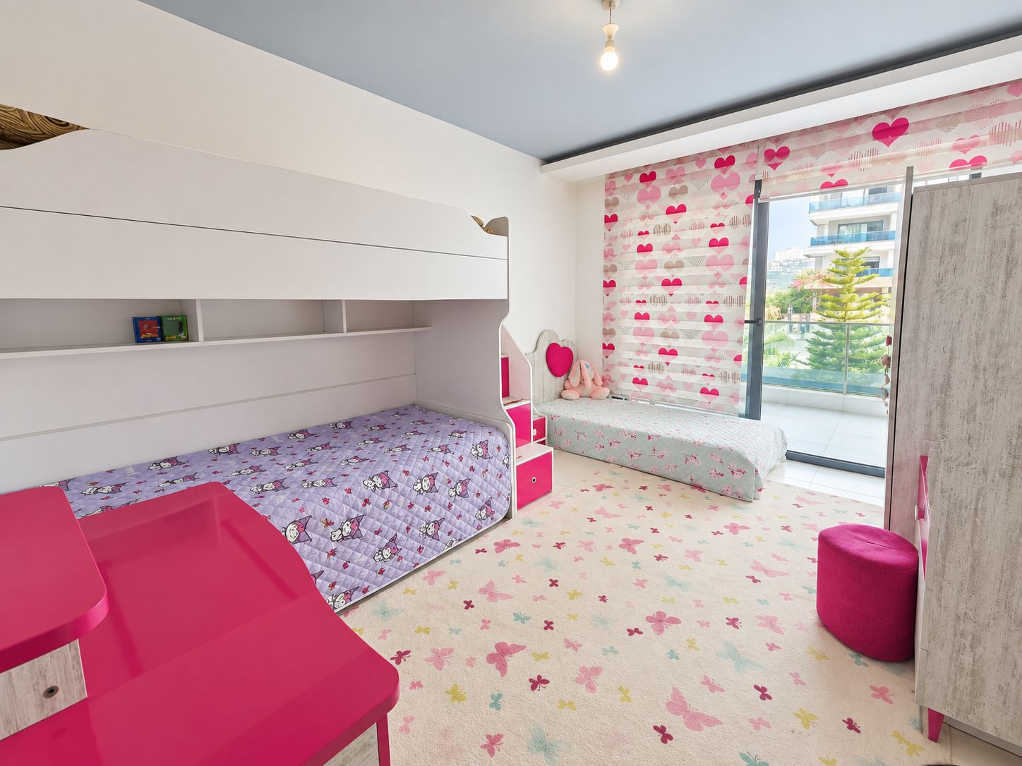 Children's bedroom with a white bunk bed, pink desk and heart-patterned wallpaper in a duplex