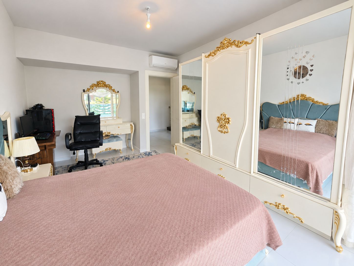 Bedroom with a pink-covered double bed, mirrored wardrobe and computer desk in Kargicak
