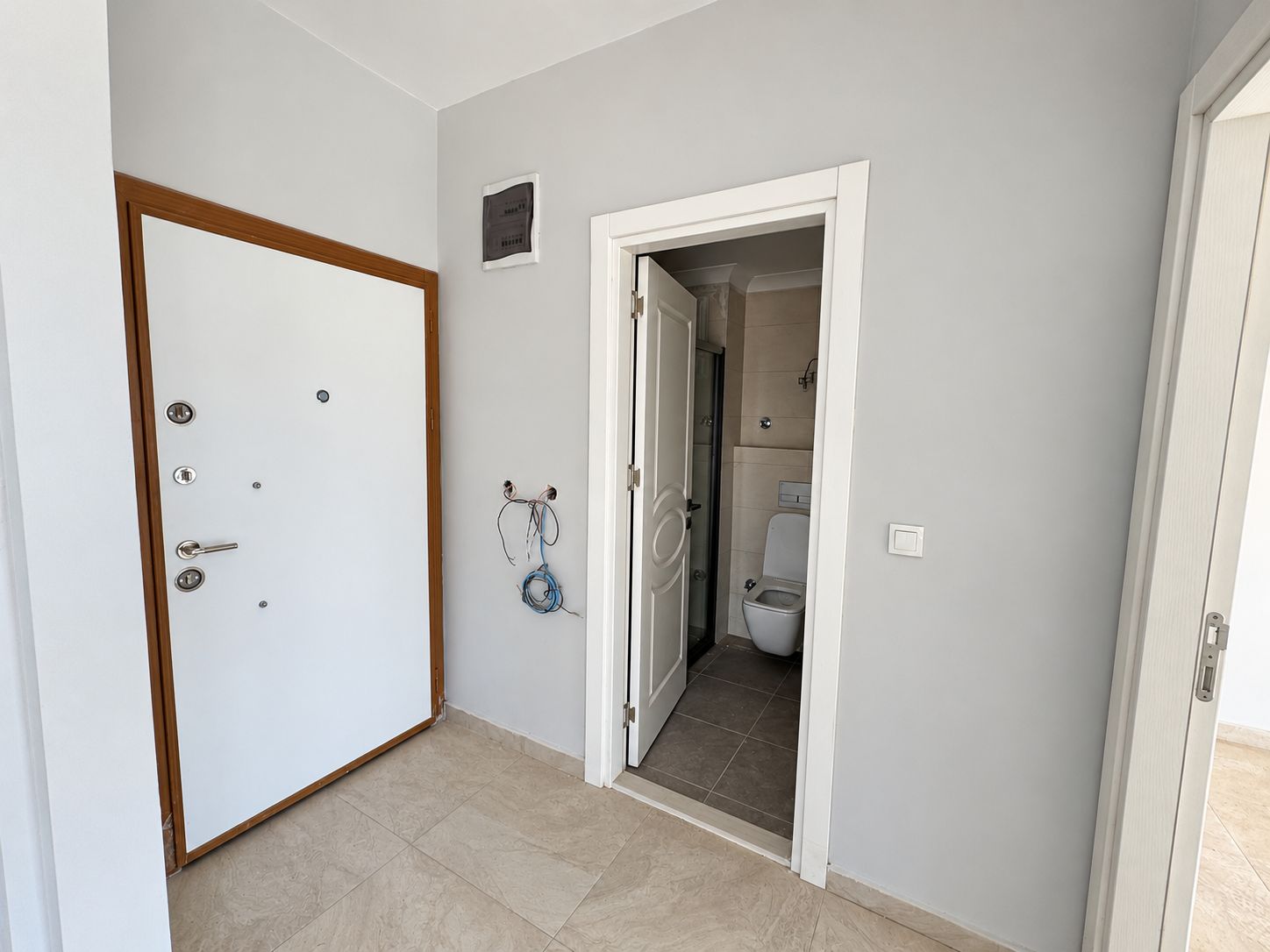 Hallway with pale tile flooring and an open bathroom door in a commercial property in Alanya
