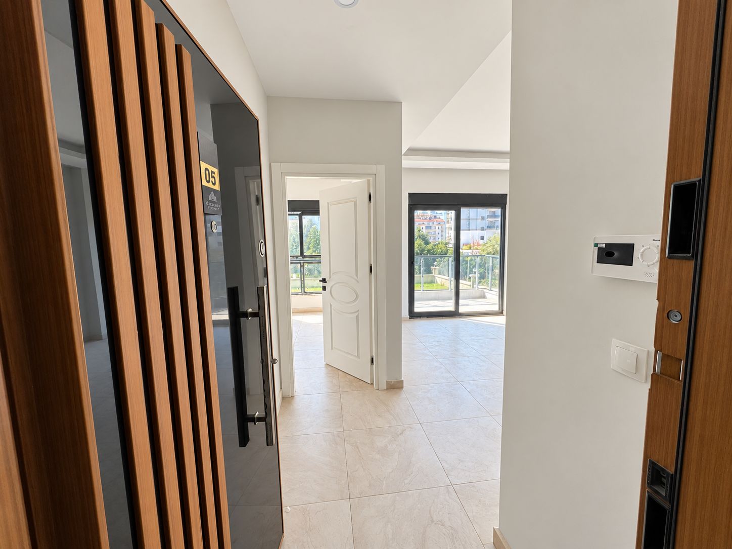 Bright entry hall with a slatted front door, black handle and sliding balcony door